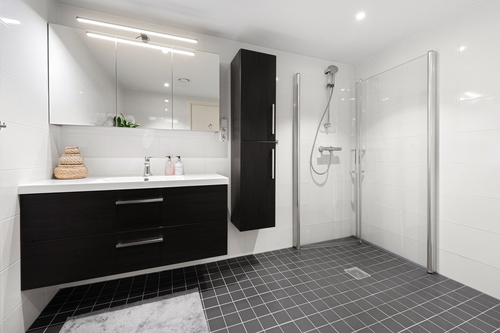 Romslig baderomsinnrdning på bad med speilskap med overlys over servant. Dusjhjørne med foldbare glassvegger Galleribilde