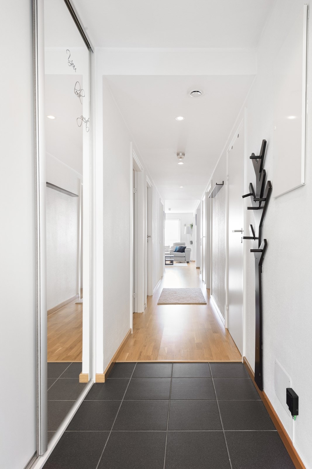 Gang/inngangsparti med fliser i tilknytning til inngangsparti samt skyvedørsgarderobe med dels speilfront som gir en god romfølelse Galleribilde