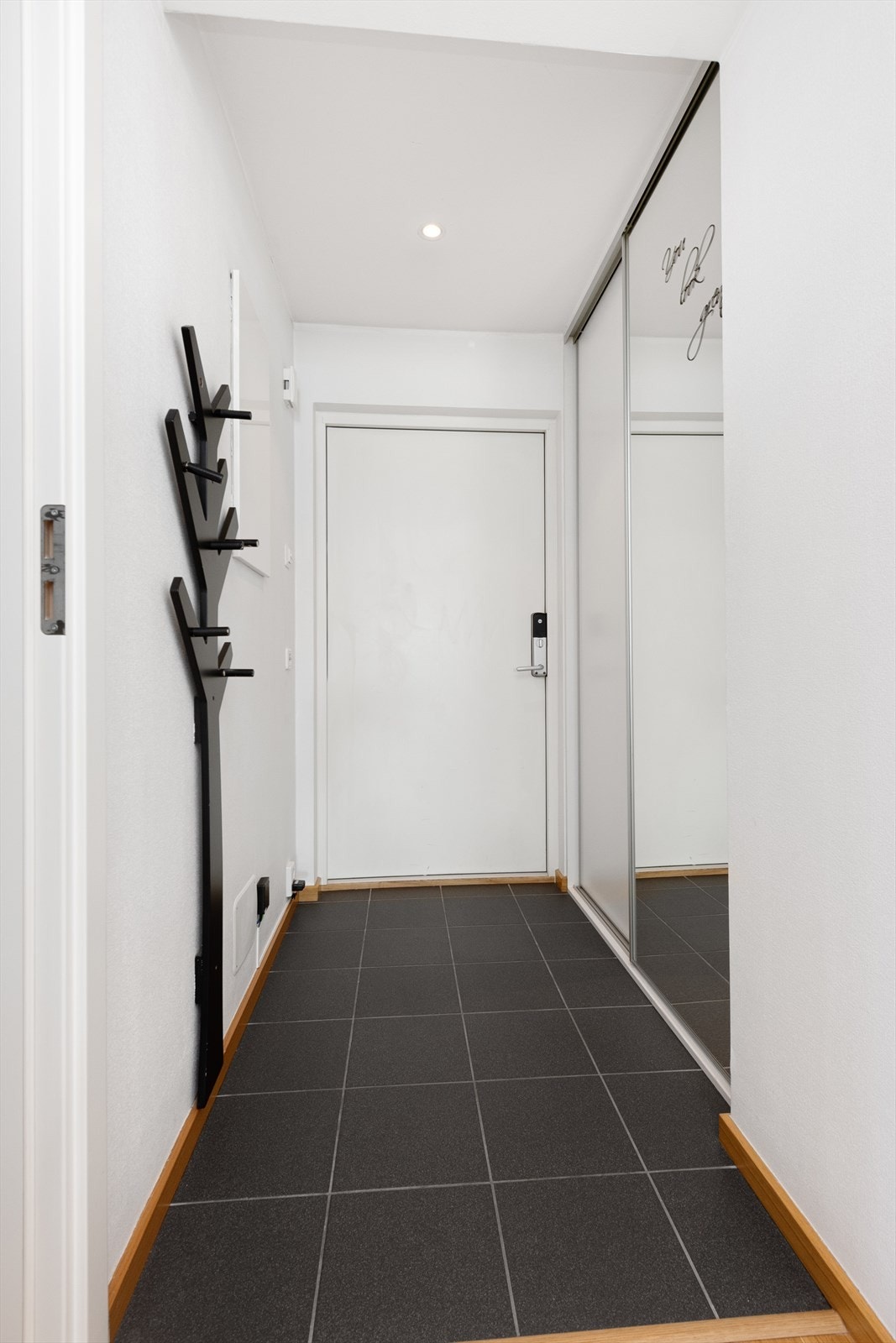 Gang/inngangsparti med fliser i tilknytning til inngangsparti samt skyvedørsgarderobe med dels speilfront som gir en god romfølelse Galleribilde