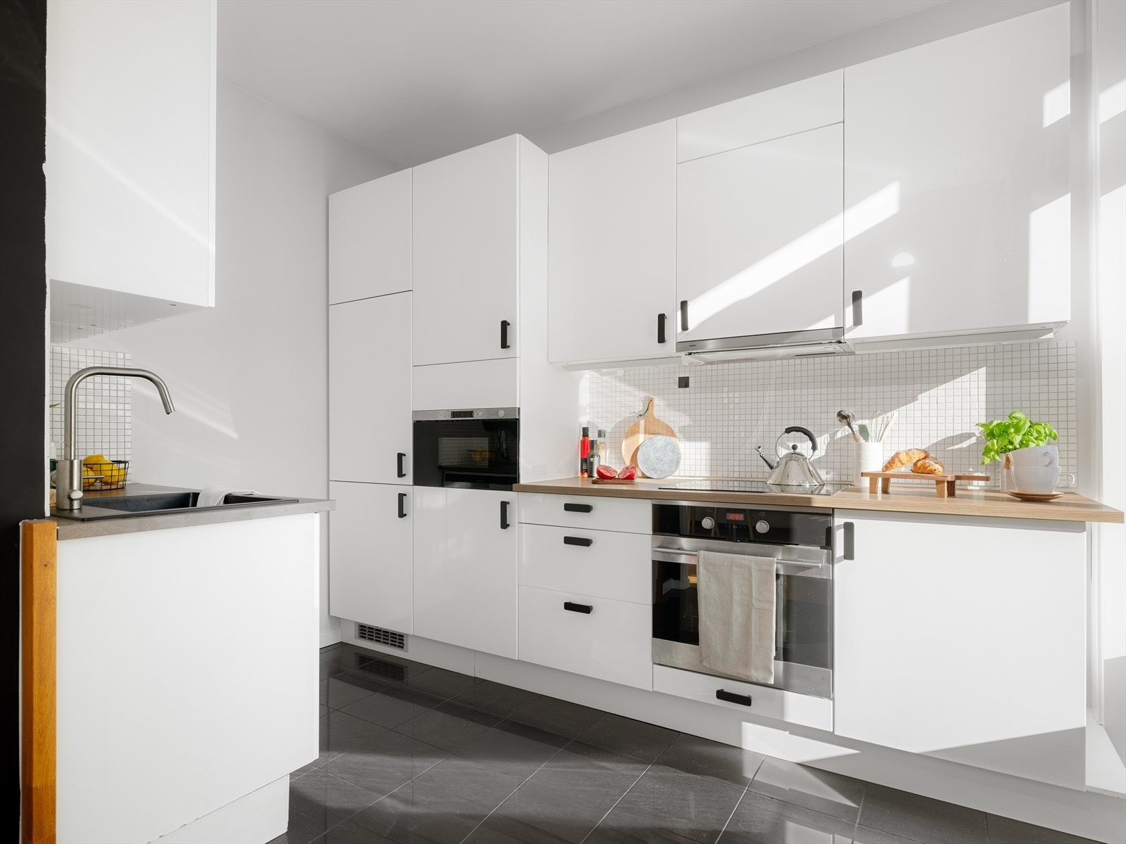 Kjøkkenet ligger i en delvis åpen løsning mot stuen. Lyst og pent kjøkken fra IKEA med laminat benkeplate. Induksjon platetopp, mikrobølgeovn og kjøl/frys er integrert i innredningen. Galleribilde