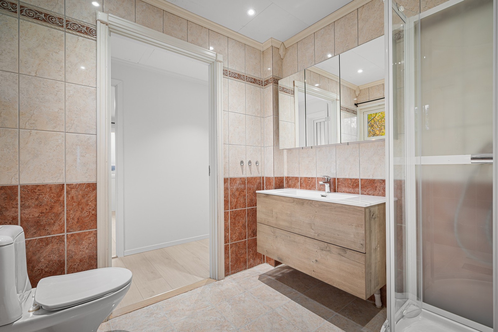 Inneholder flott servantinnredning med god plass i skuffer, praktisk overskap med speil, dusjkabinett og wc Galleribilde