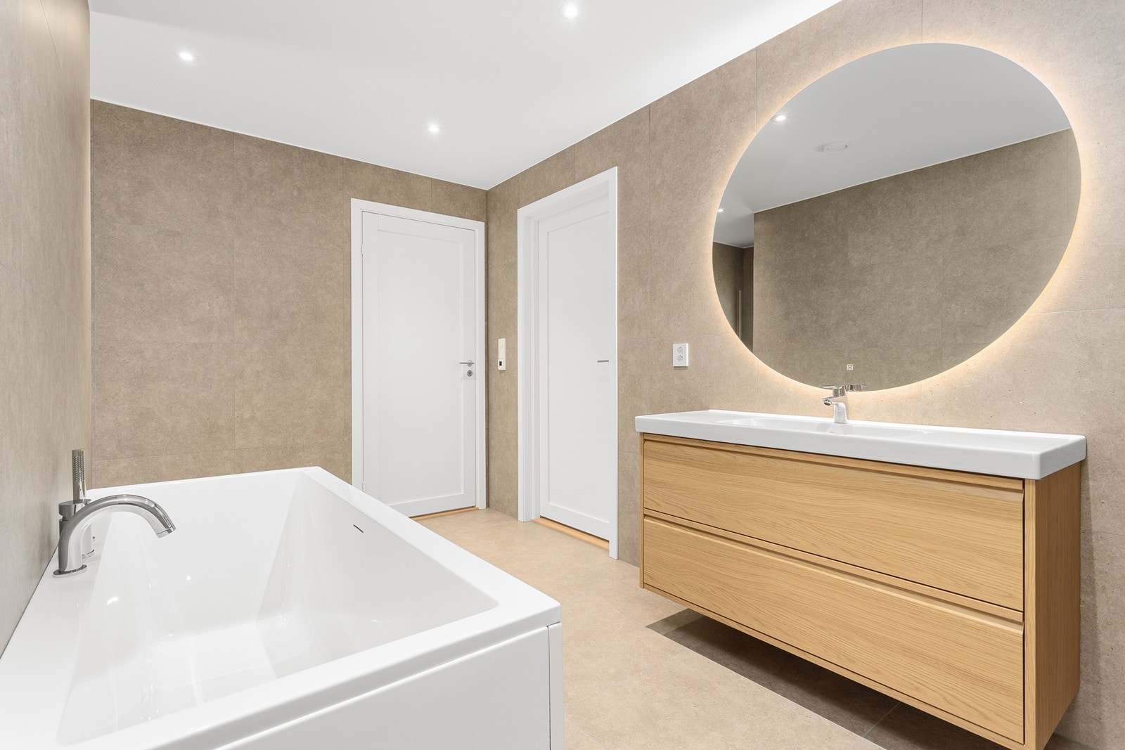 Badet er utstyrt med heldekkende nedfelt servant med plass til oppbevaring i skuffer, speil over servant med integrert LED-lys for det perfekte speilbildet og badekar. Galleribilde