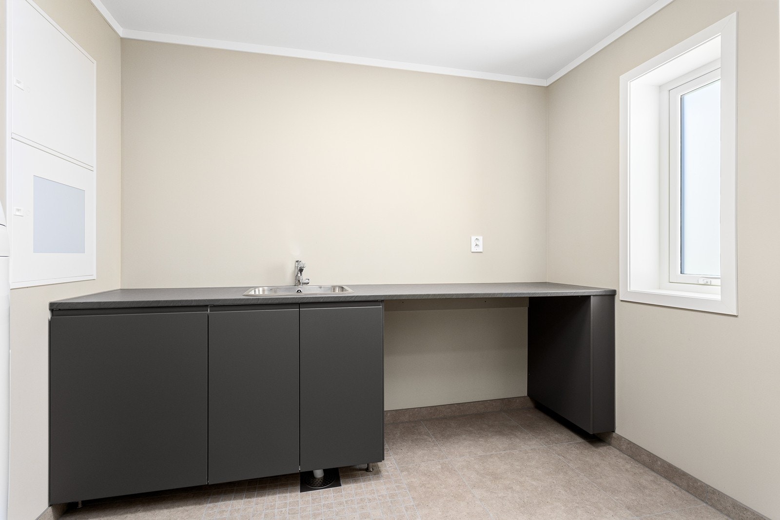 Praktisk vaskerom med innredning med nedfelt stål-servant og opplegg for vaskemaskin og tørketrommel. Galleribilde