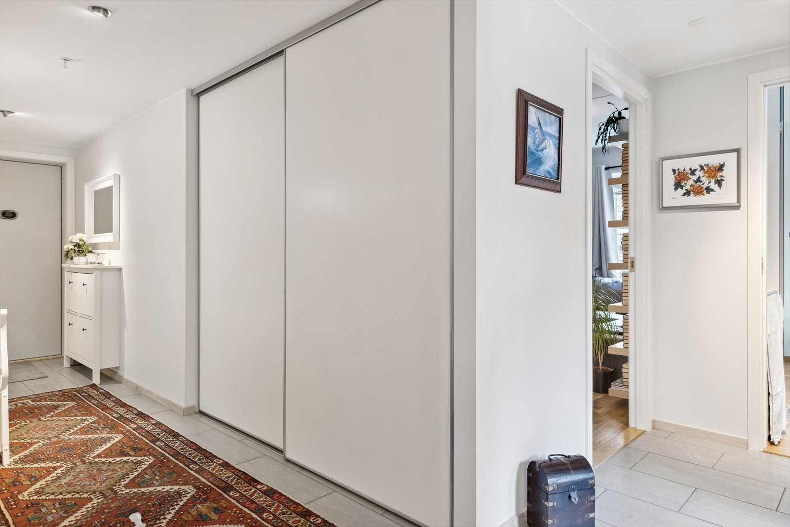 Yttertøyet kan ryddes unna i en plassbygd skyvedørsgarderobe med hvite, glatte fronter. Galleribilde