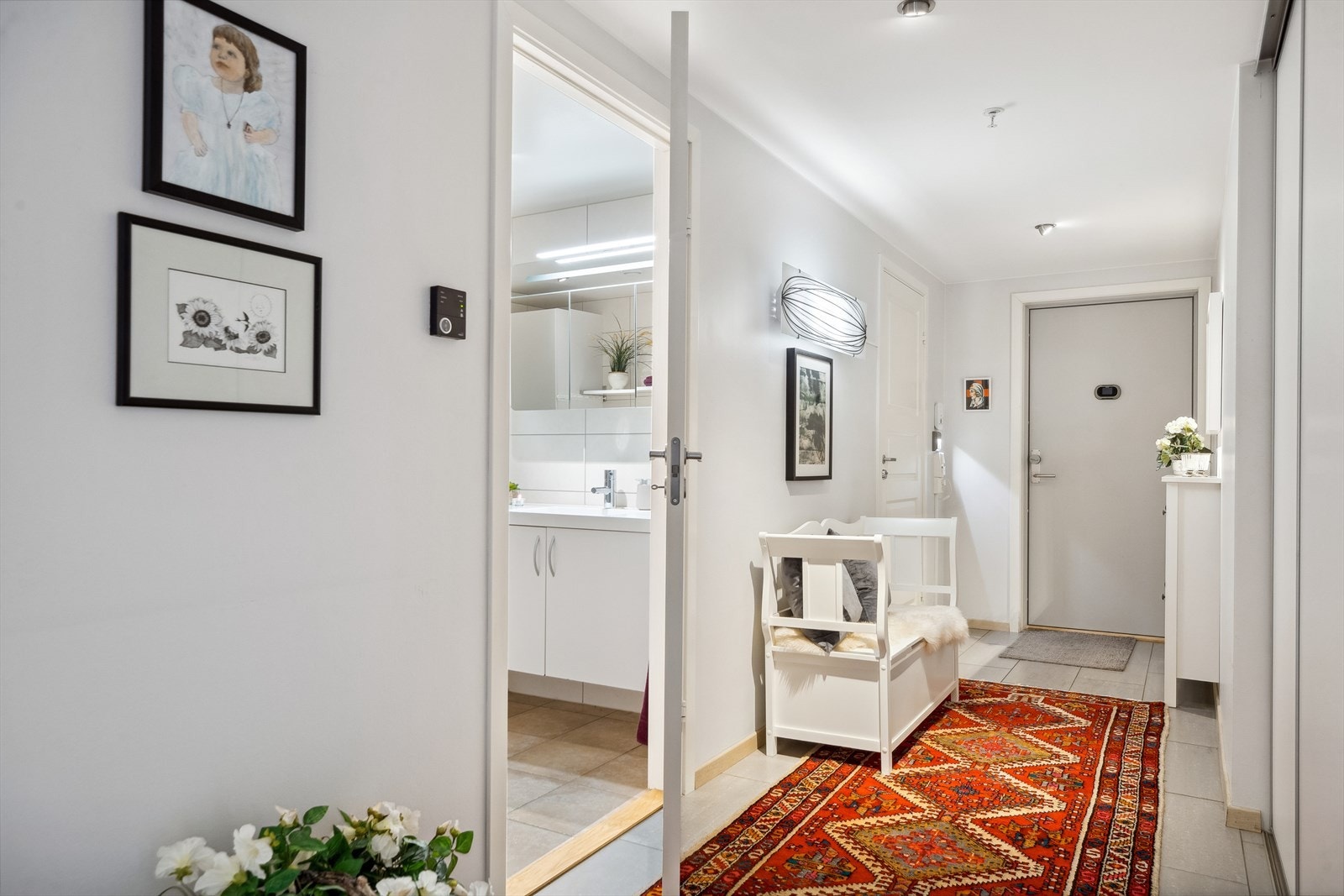 Med lyse vegger, innfelte spotter og flislagt gulv gir entreen et pent førsteinntrykk av leiligheten. Galleribilde