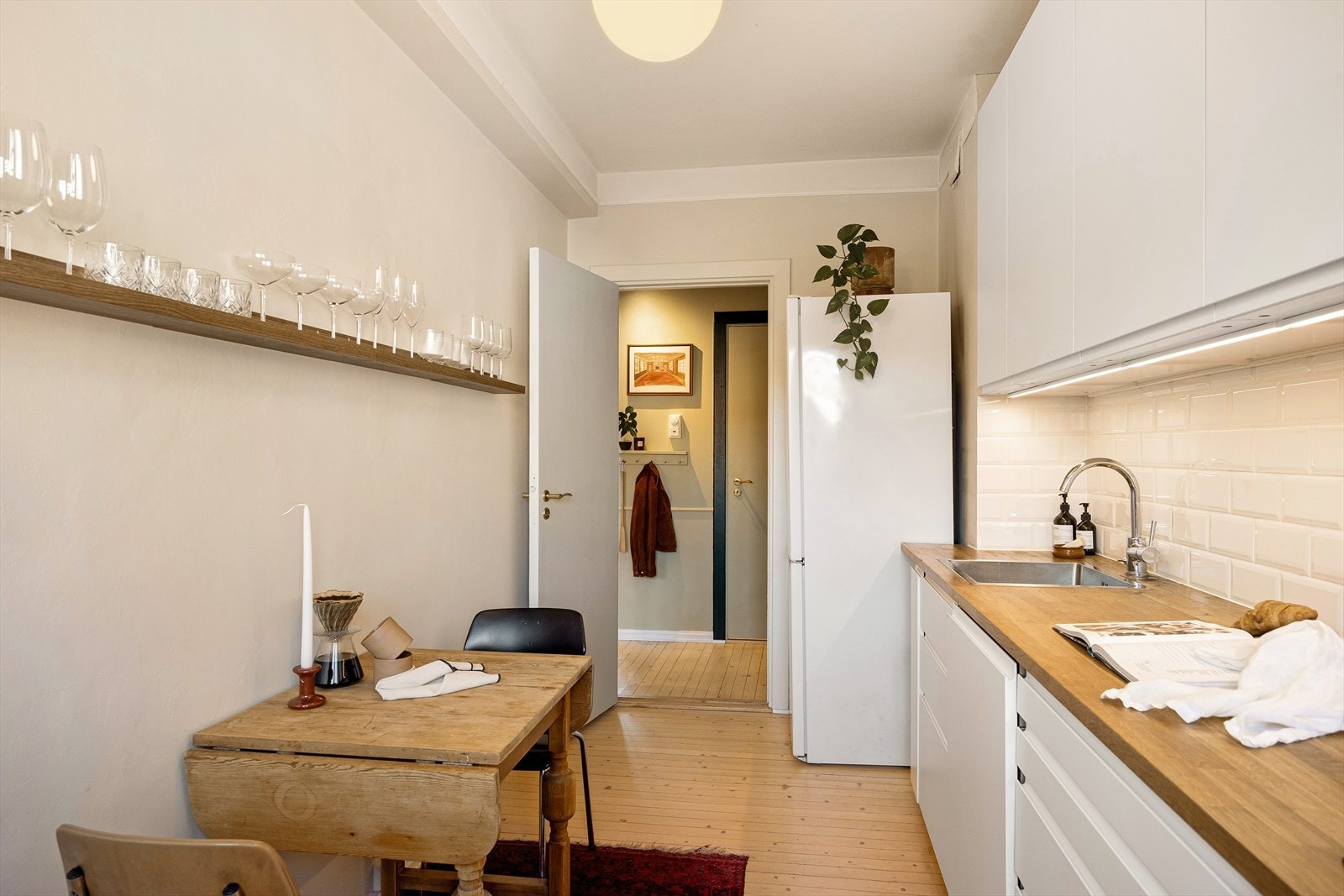 Tidsriktig innredning med glatte fronter, fliser på vegg over kjøkkenbenk og heltre benkeplate. Galleribilde