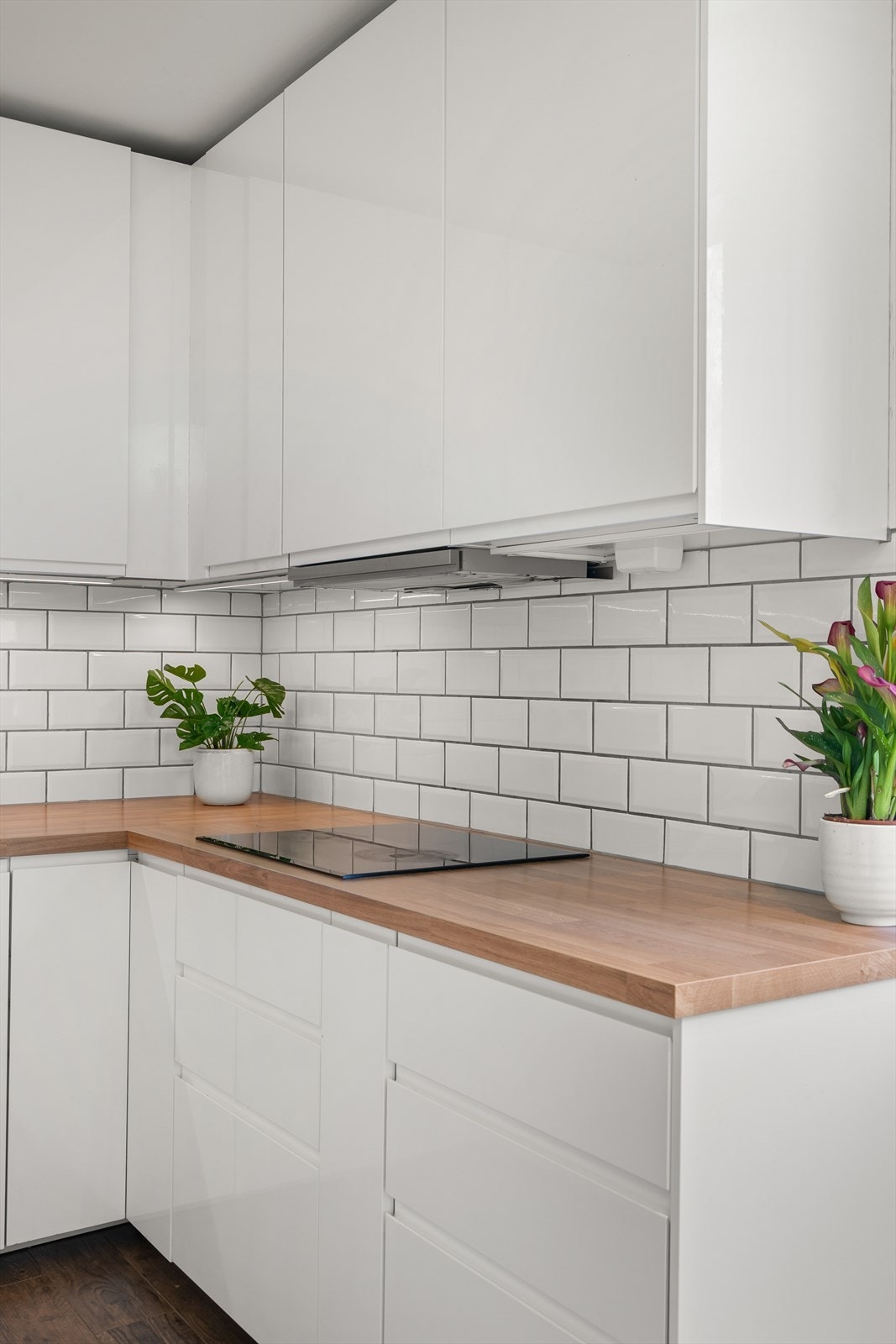 Kjøkkeninnredning fra Ikea fremstår med glatte fronter.
Laminert benkeplate med oppvaskkum og 1-greps blandebatteri. Lys under overskap, ventilator med kullfilter. Galleribilde