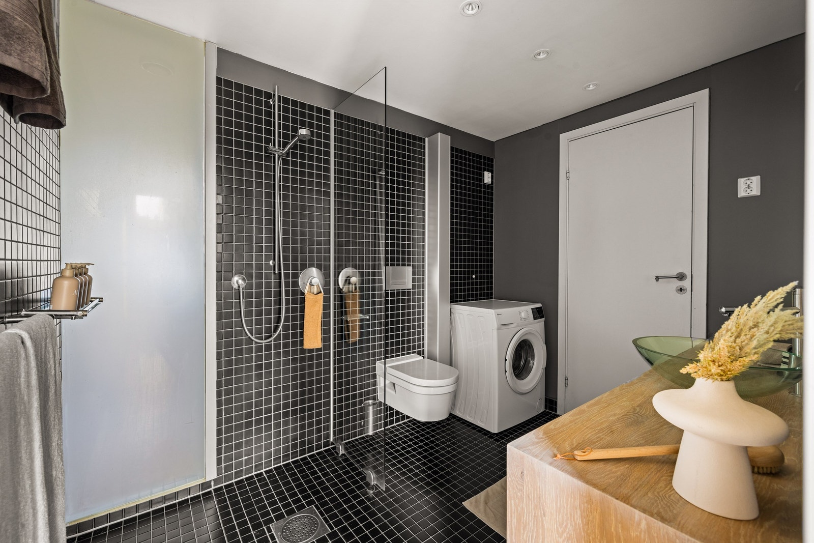 Veggparti i frostet glass mot stue gir badet naturlig lys. Galleribilde