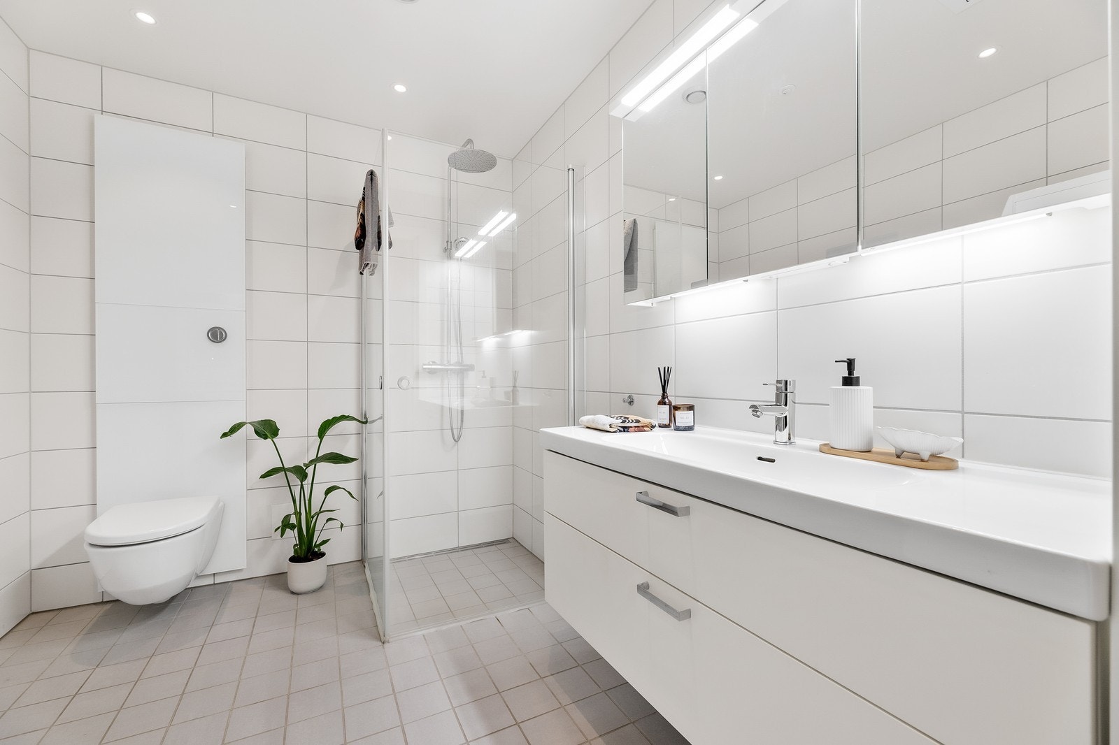 Badet har lyse fliser, en stor servant, dusjhjørne og toalett. Galleribilde