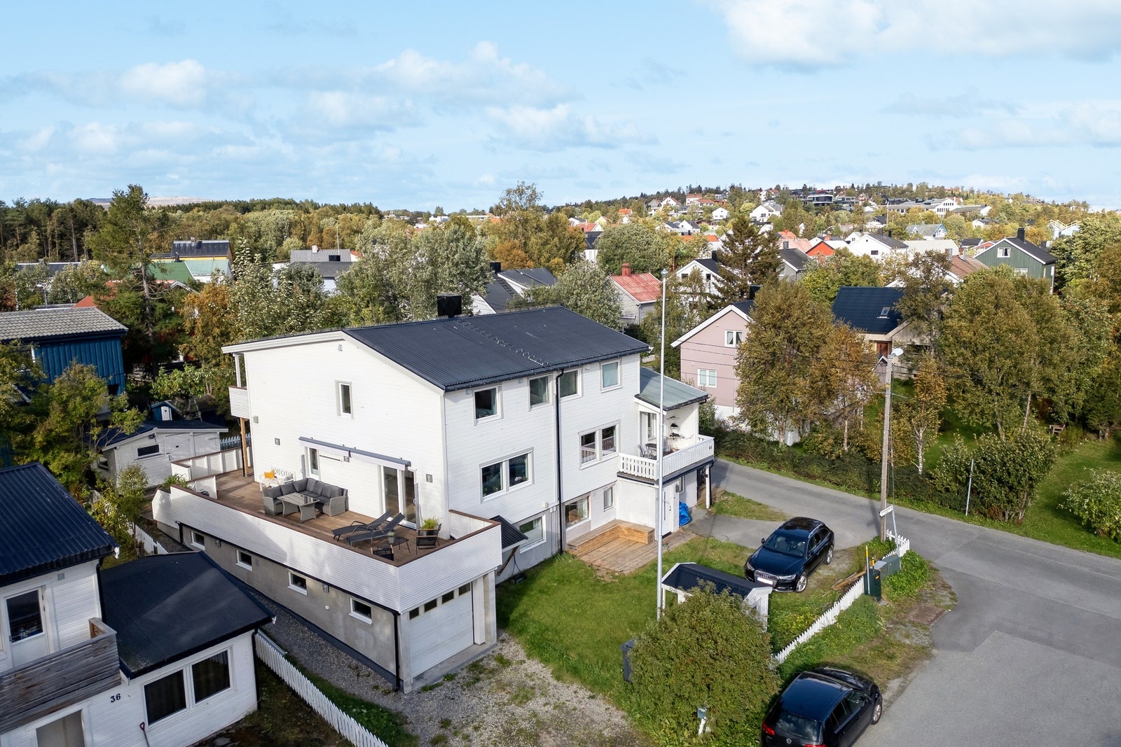 Thorshaugvegen 42 er en vertikaldelt bolig i tidløse farger med gressplen og parkering i garasje Galleribilde