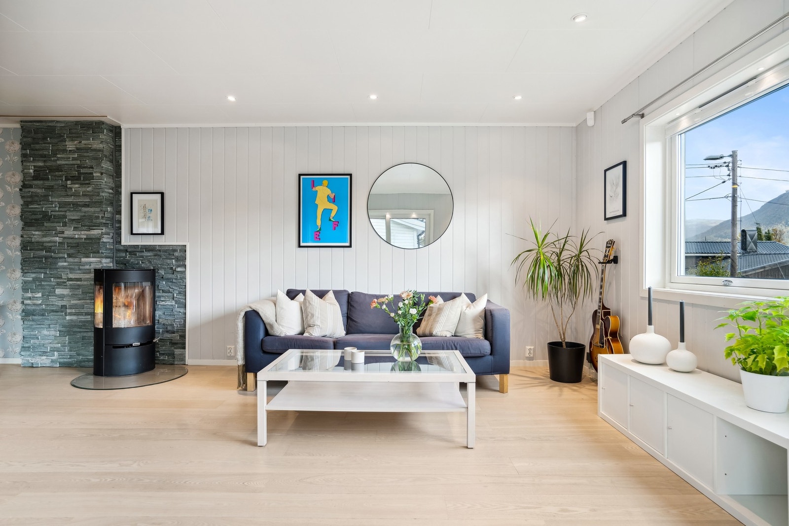 Boligen er godt vedlikeholdt med moderne farge- og interiørvalg, samt flott vedovn med stilfull steinvegg bak Galleribilde