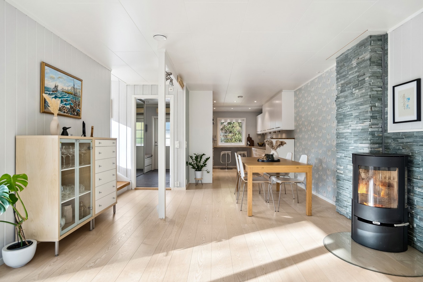 Etasjen har åpen løsning mellom kjøkken, spisestue og stue med tidløse fargevalg, samt flott tapet bak spisebordet Galleribilde