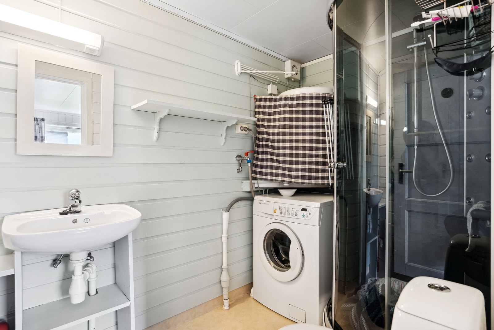 Utleiedelens bad har lyse overflater og det er god plass til dusjkabinett, vaskemaskin Galleribilde