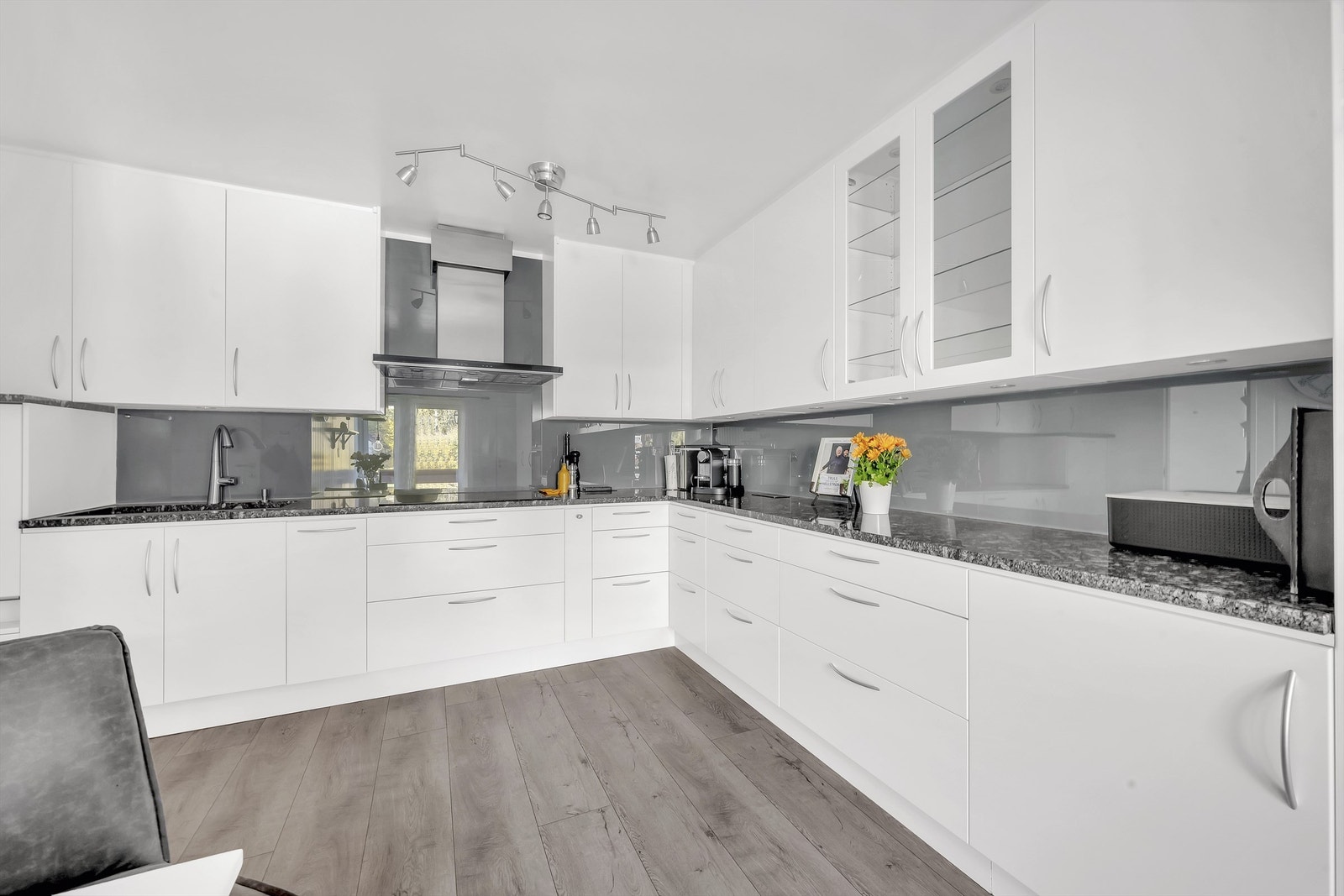 En praktisk glassplate mellom kjøkkenbenk og overskap beskytter veggen og gjør renholdet enkelt Galleribilde