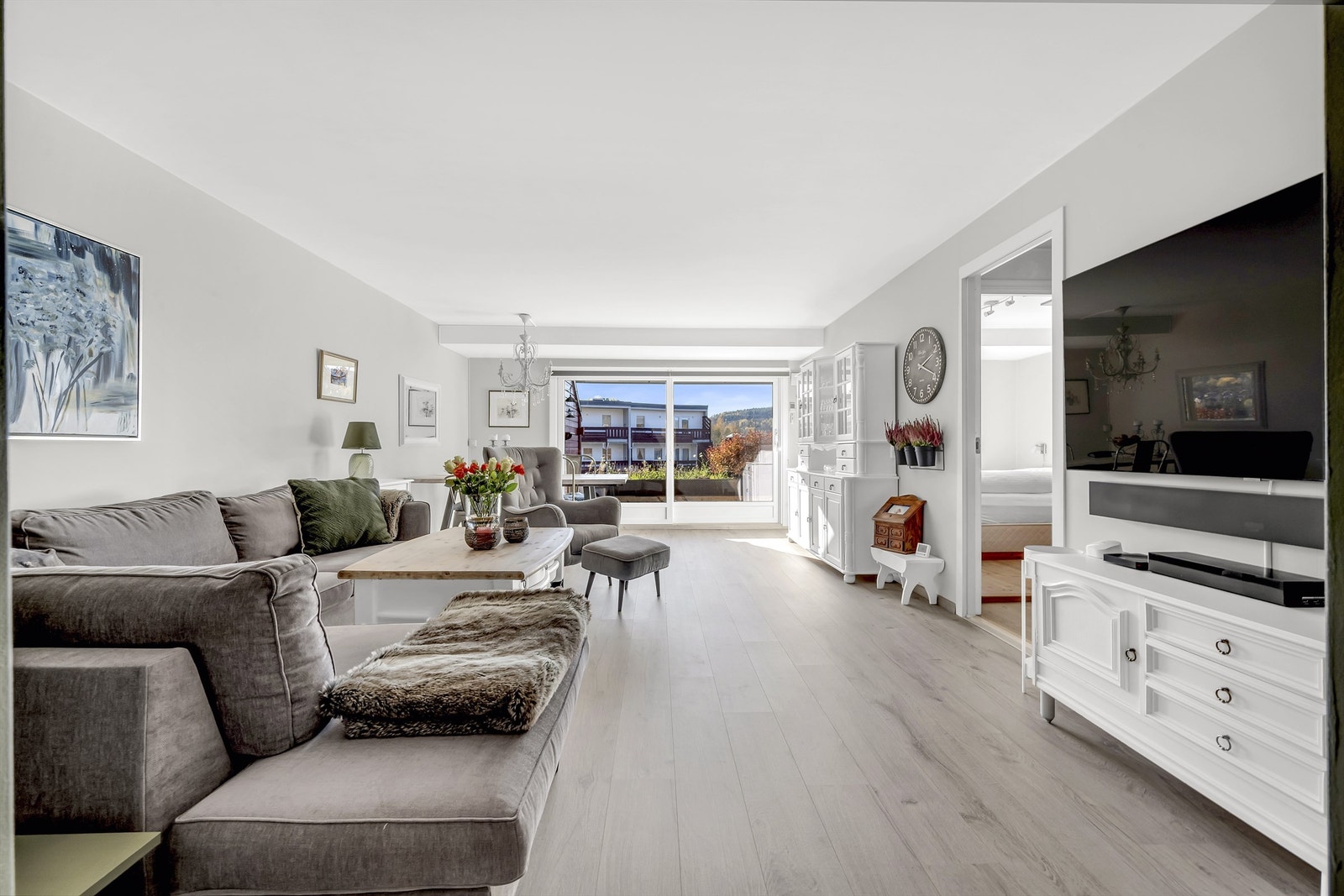 Stuen har store vinduer som gir rikelig med lysinnslipp og utgang til en solrik terrasse Galleribilde