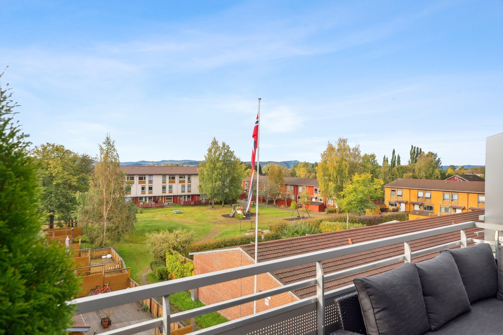 Varme dager nytes på en herlig balkong utenfor stuen, med vidstrakt utsikt mot felleshagen og fine fjell i det fjerne. Galleribilde