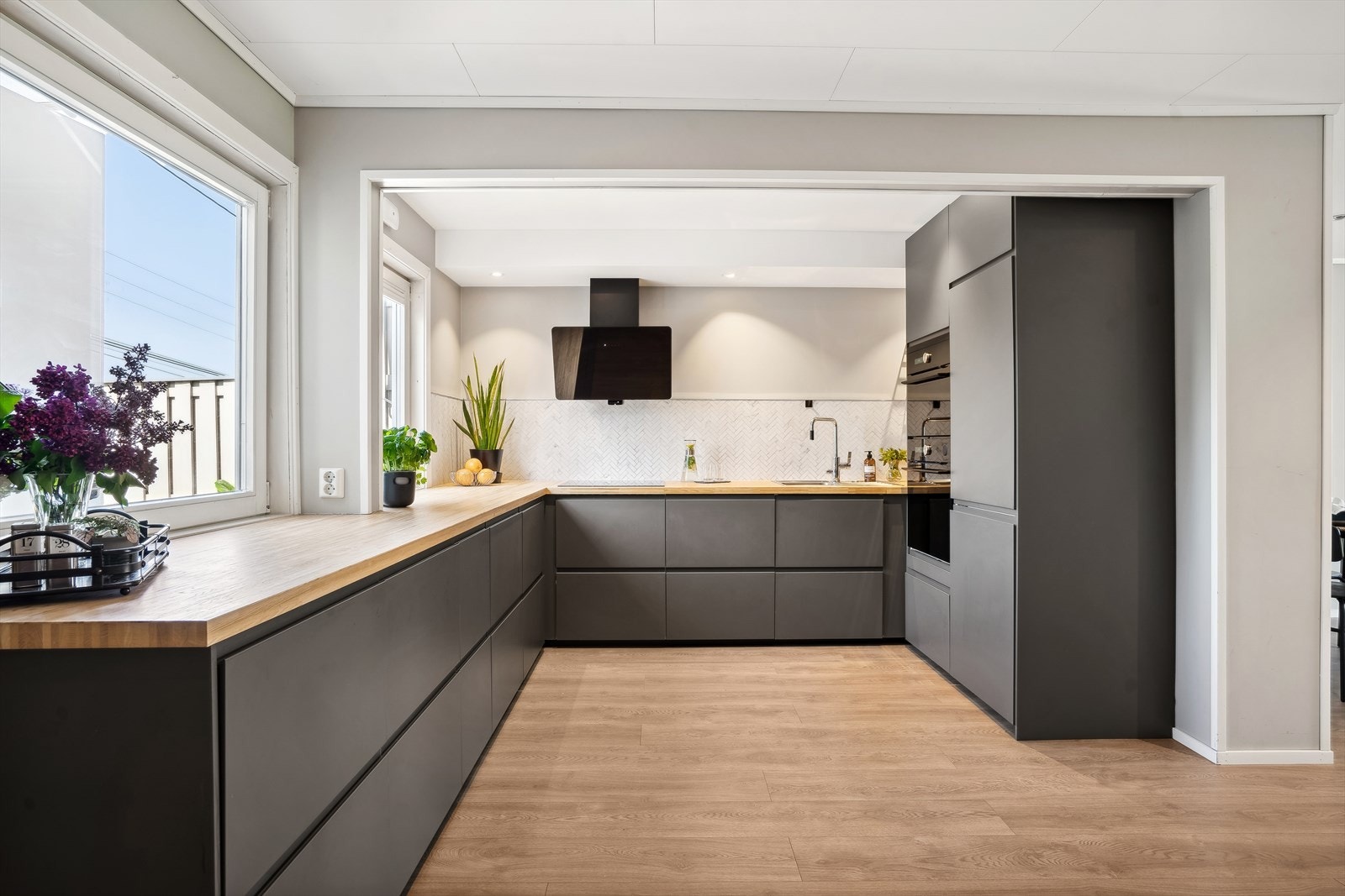 IKEA kjøkkeninnredning med glatte fronter, heltre benkeplate med nedfelt vaskekum, fliser over benkeplate. Her er det rikelig av skap- og benkeplass. Galleribilde