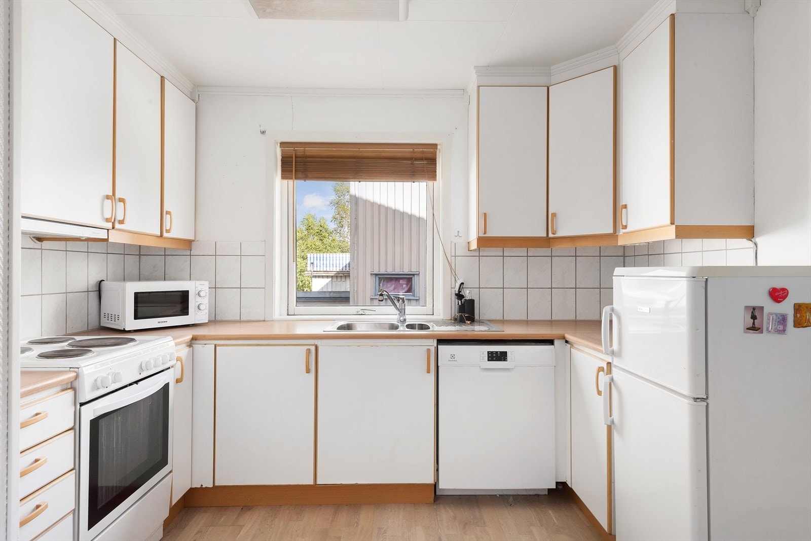 Kjøkkeninnredning av laminerte skrog med laminerte malte slette fronter og laminert benkeplate. Galleribilde
