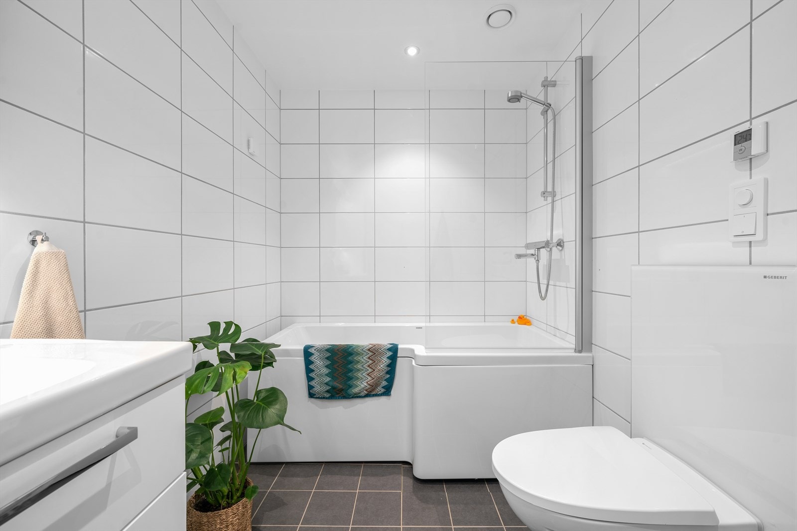 Begge rommene har en klassisk stil med hvite fliser på veggene, grå fliser med vannbåren gulvvarme, downlights i himlingen og vegghengt toalett. Galleribilde