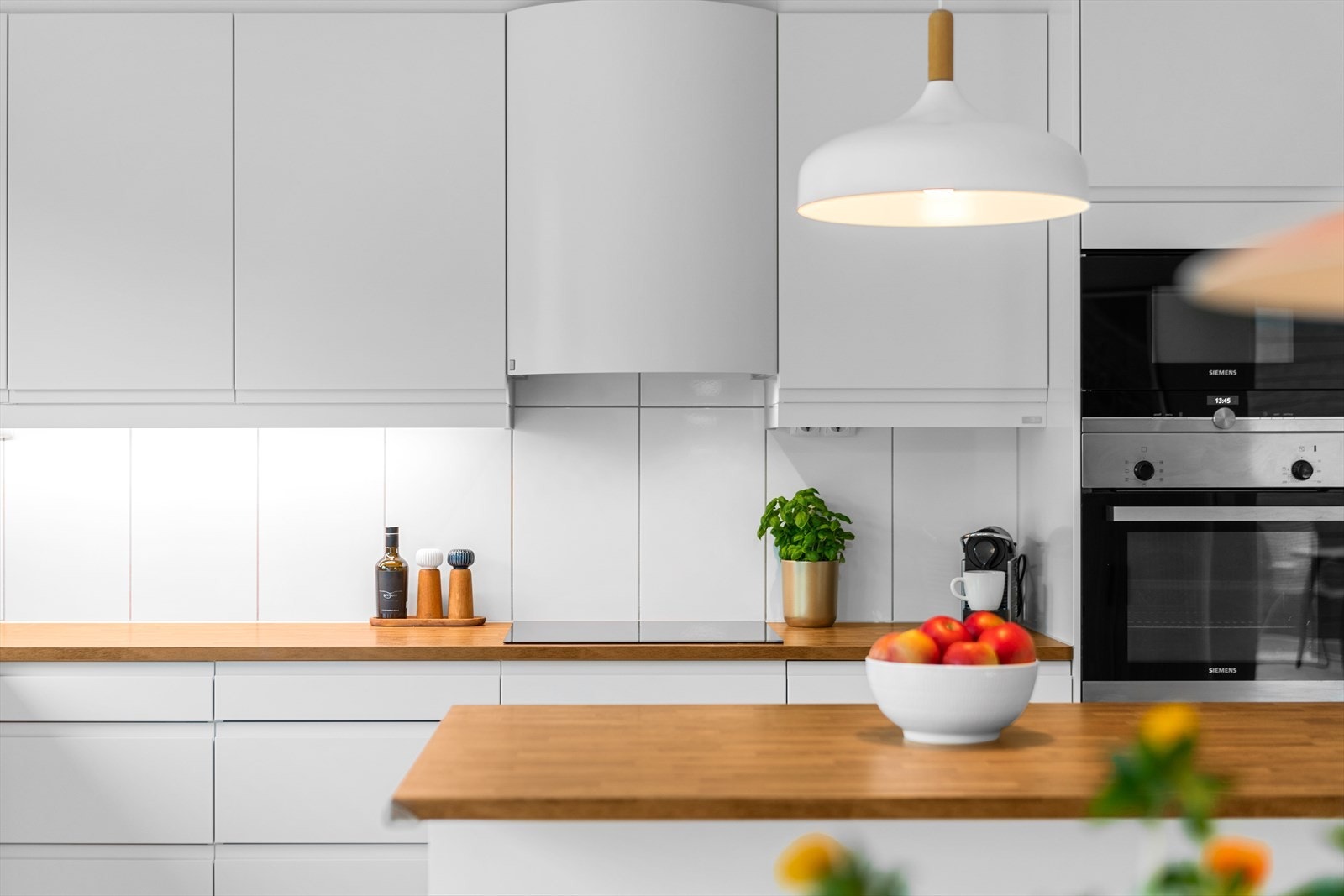Over koketoppen er det store, hvite veggfliser og hvit ventilator med avtrekk til ventilasjonsanlegget. Galleribilde