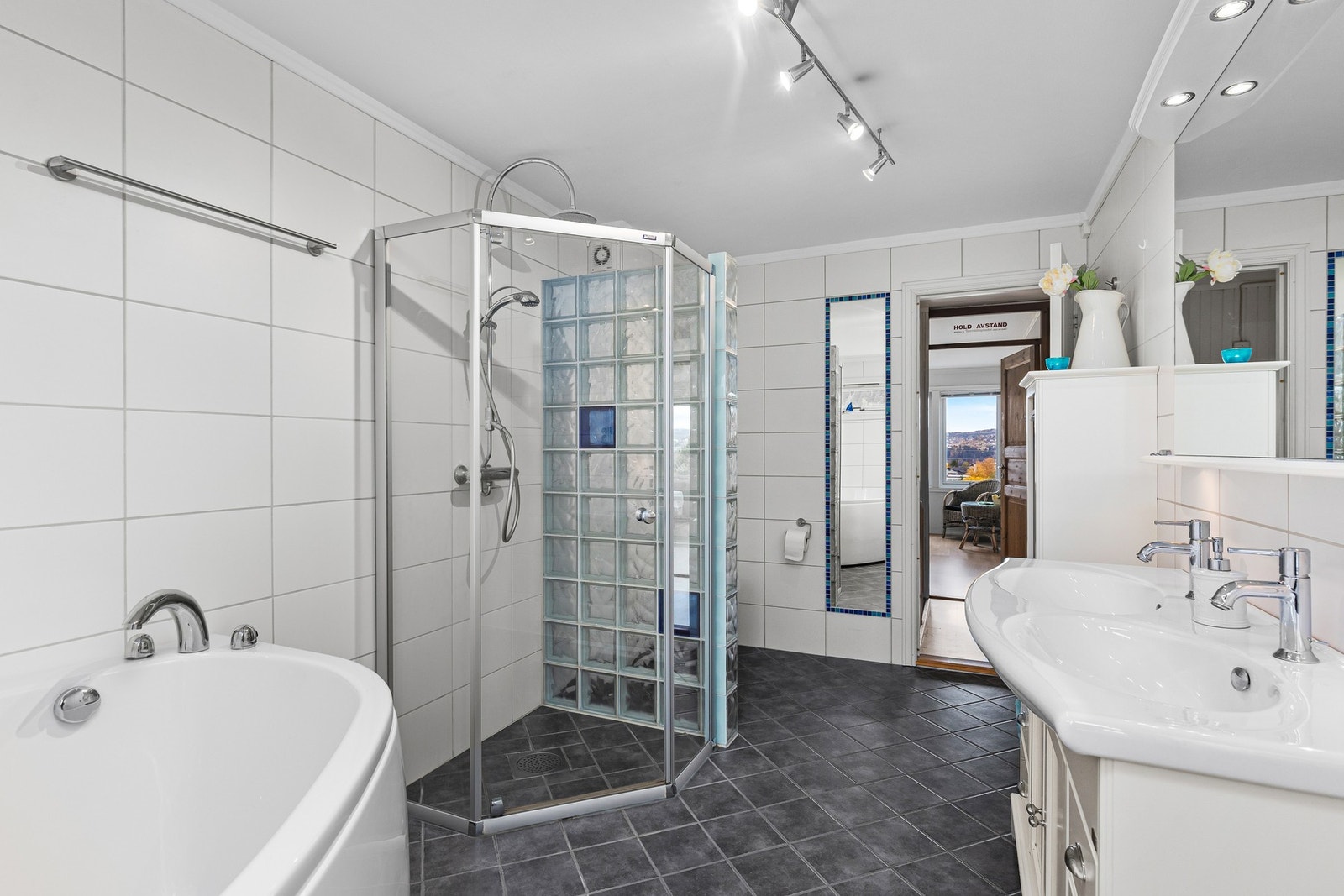 Badet er innredet med badekar, dobbel servant, dusjnisje og toalett. Galleribilde