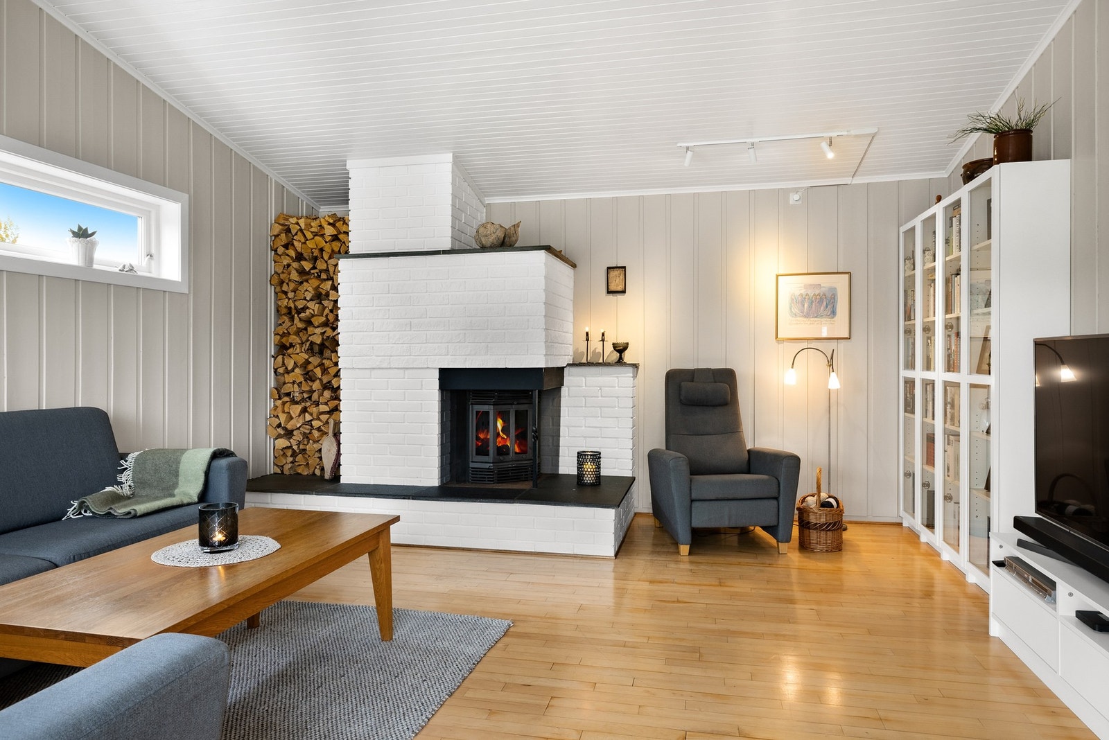 Hjemmekoselig preg med murt peis med lukket peisinnsats på stue i tilbygg Galleribilde