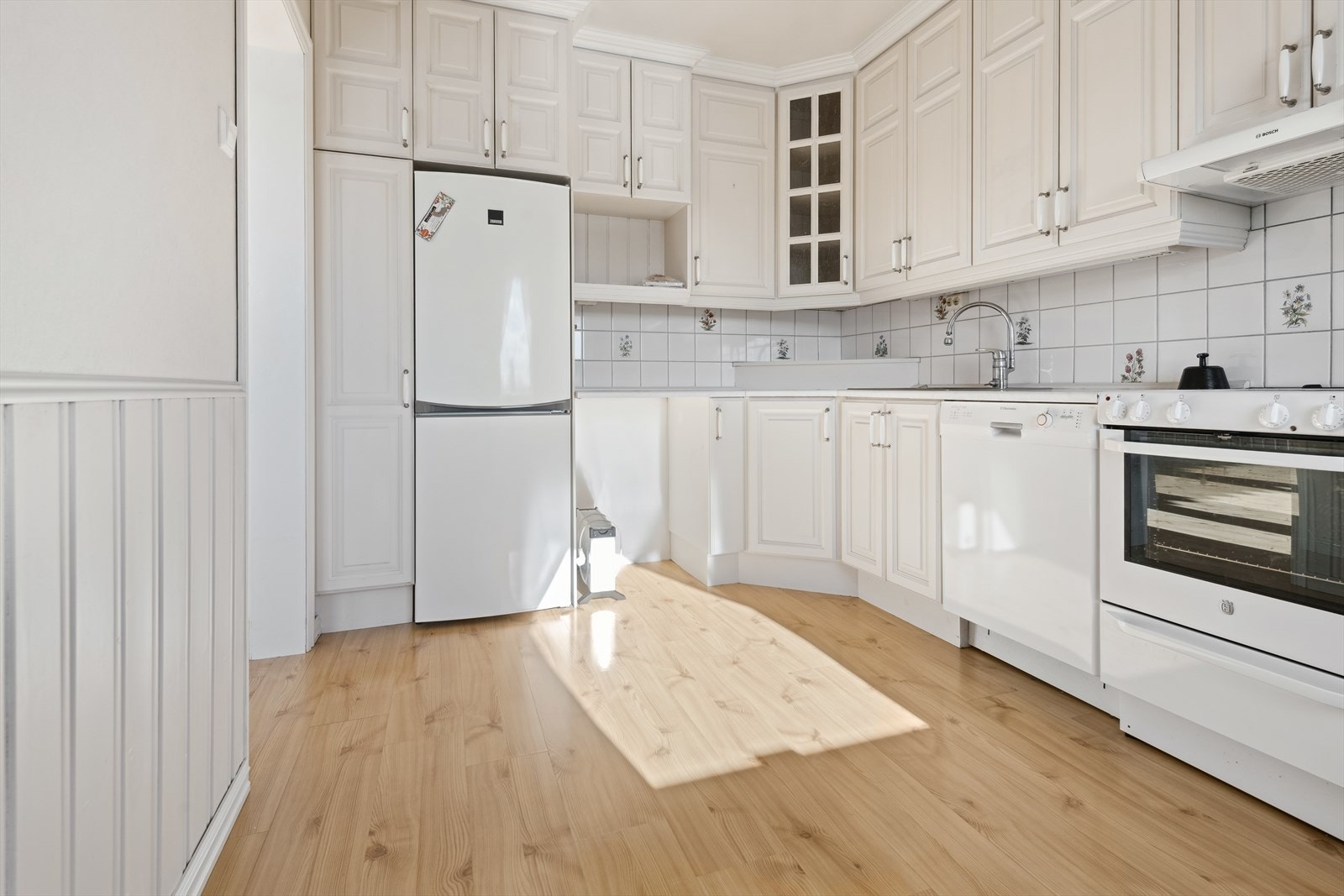 Romslig kjøkken med en hvitmalt, heltre innredning fra 2007. Galleribilde