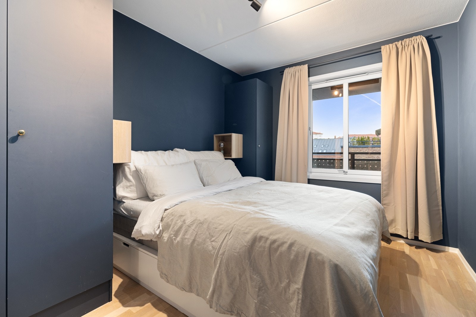 Stor dobbeltseng med nattbord montert på hver side av sengen Galleribilde