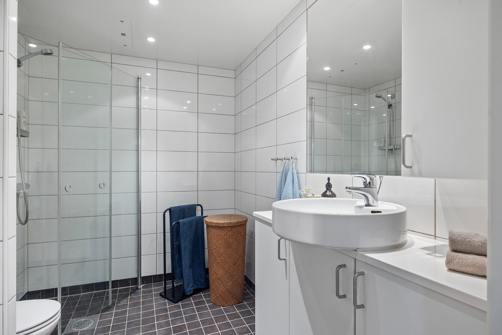 Romslig og lyst flislagt baderom med gulvvarme og downlights i taket. Galleribilde