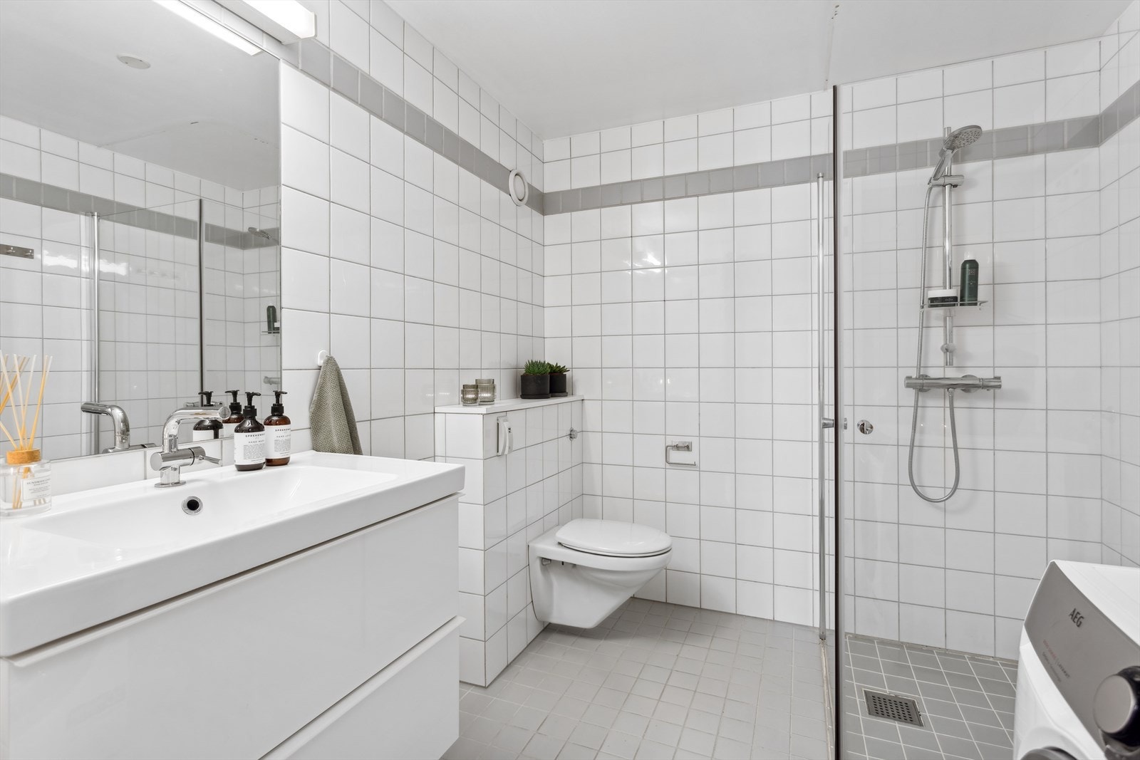 Bad/wc består av vegghengt wc, servant m/underskap, innfliset speil m/overlys, inn-/utadslående dusjdører og opplegg for vaskemaskin. Galleribilde