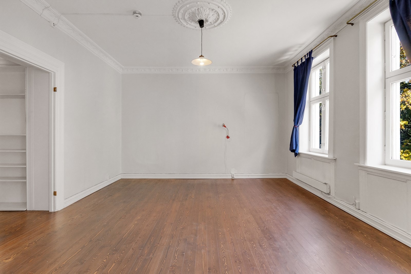 Fire klassiske vinduer på rekke, stukkatur og rosett gir denne leiligheten sjarm og sjel Galleribilde