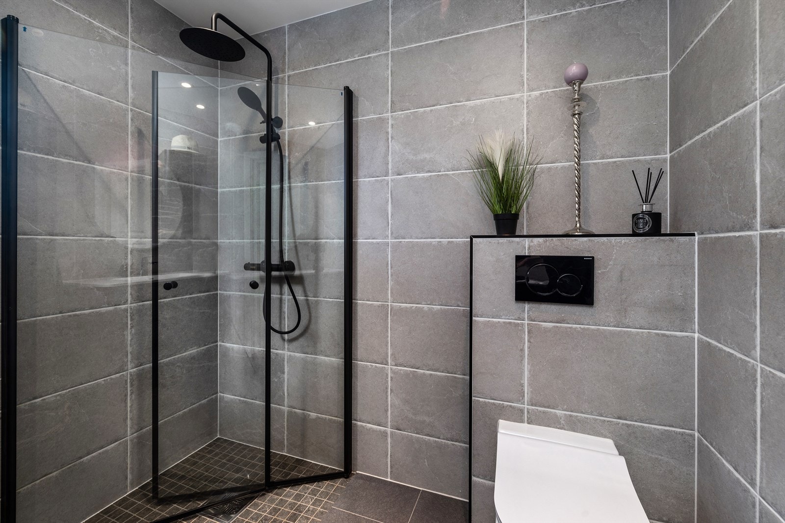 Badet inneholder servantinnredning, vegghengt toalett og dusjhjørne med dusjvegger. Galleribilde