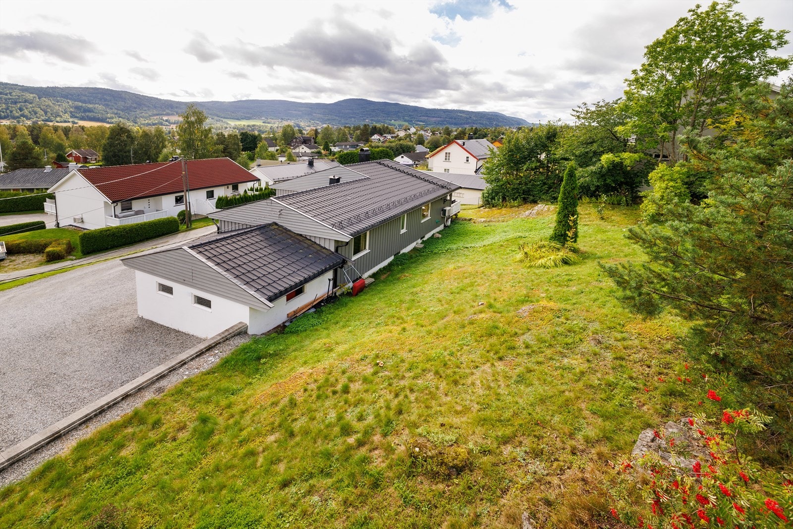 Uteområdet er pent opparbeidet med en romslig gruset gårdsplass, forstøtningsmurer, plen og diverse beplanting. Galleribilde