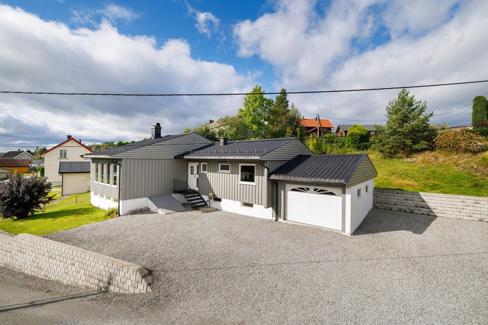 Eiendommen har en romslig gruset gårdsplass, pent opparbeidet med støttemurer. Galleribilde