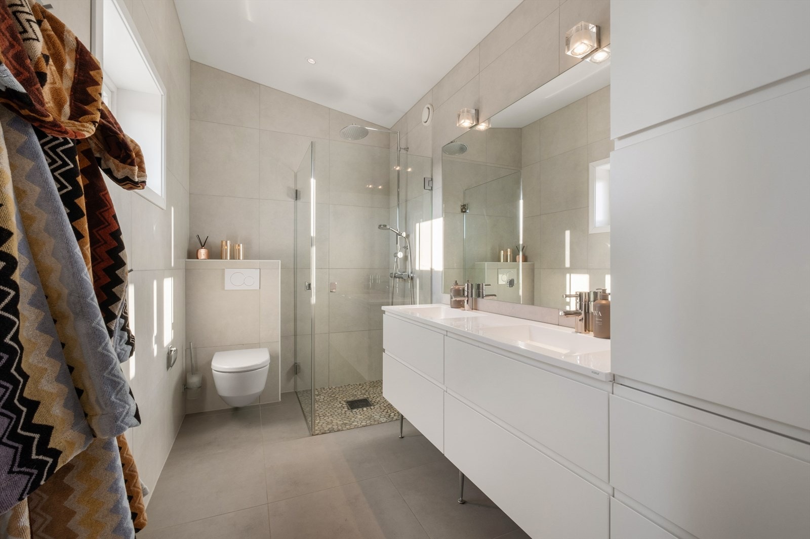 Her fra boligens andre bad. Ekstra takhøyde i deler av badet. Store fliser på gulv med rullesten i dusj. Dobbel servant, godt med skuffer og skap. Galleribilde