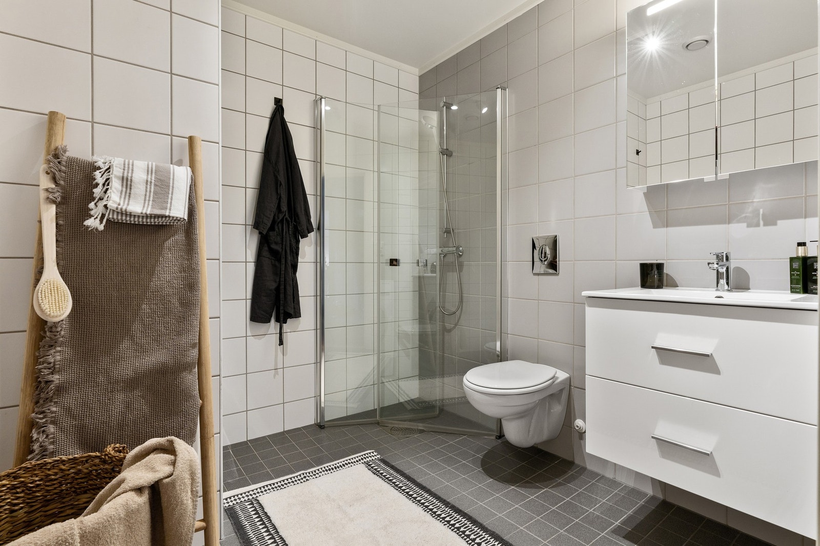 Videre er badet utstyrt med vegghengt toalett, lys baderomsinnredning og overspeil med integrert lys. Galleribilde