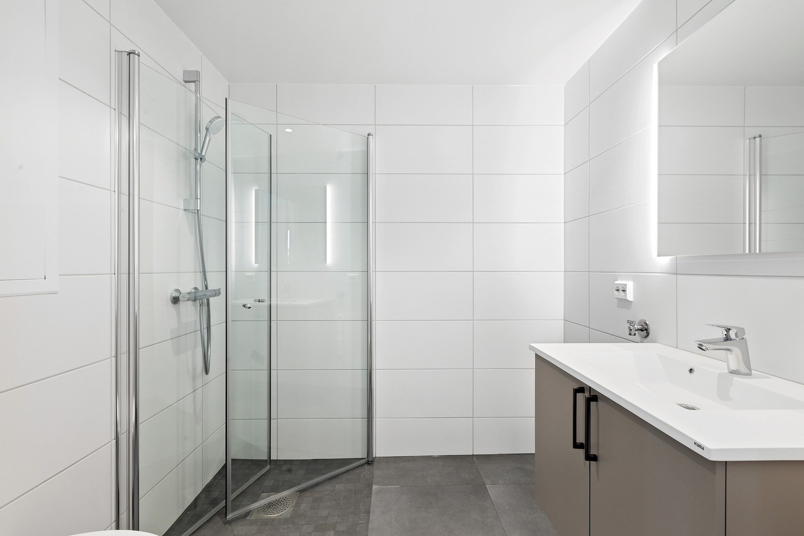 Flislagt bad med dusjhjørne, servant med innredning og opplegg for vaskemaskin Galleribilde