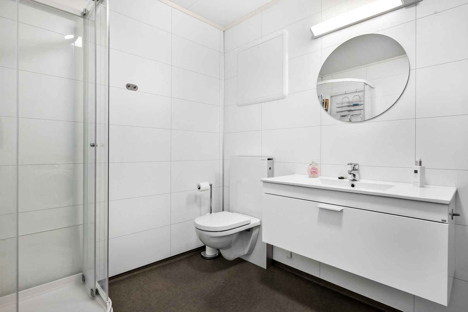 Romslig bad med overflater av baderomsplater på vegger og belegg på gulv Galleribilde