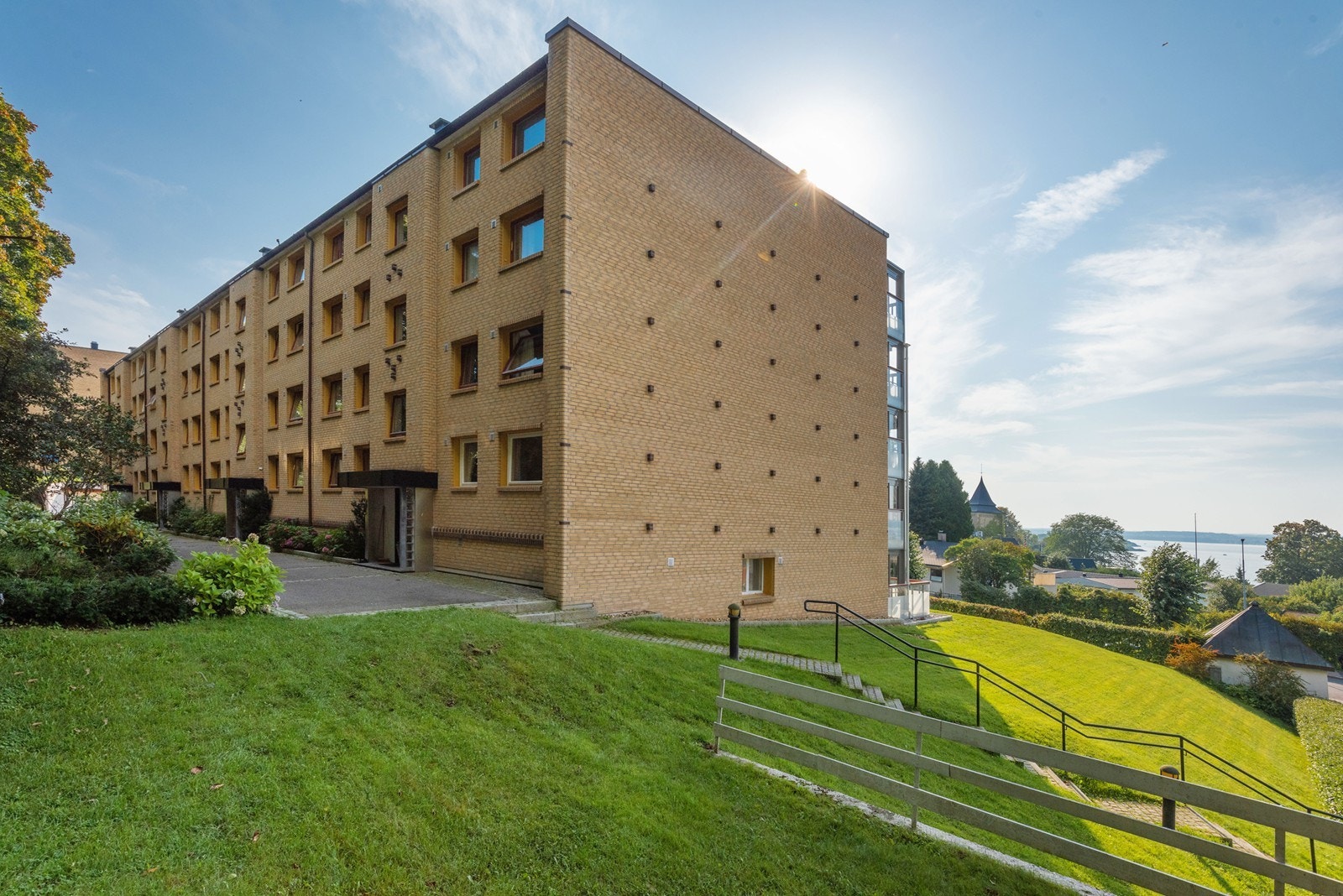 Tomten er pent opparbeidet med gressplen, div. beplantning, busker, hekk, trær m.m. I bakgrunn ser man toppen av Refsnes Gods som ligger en kort gåtur unna. Galleribilde