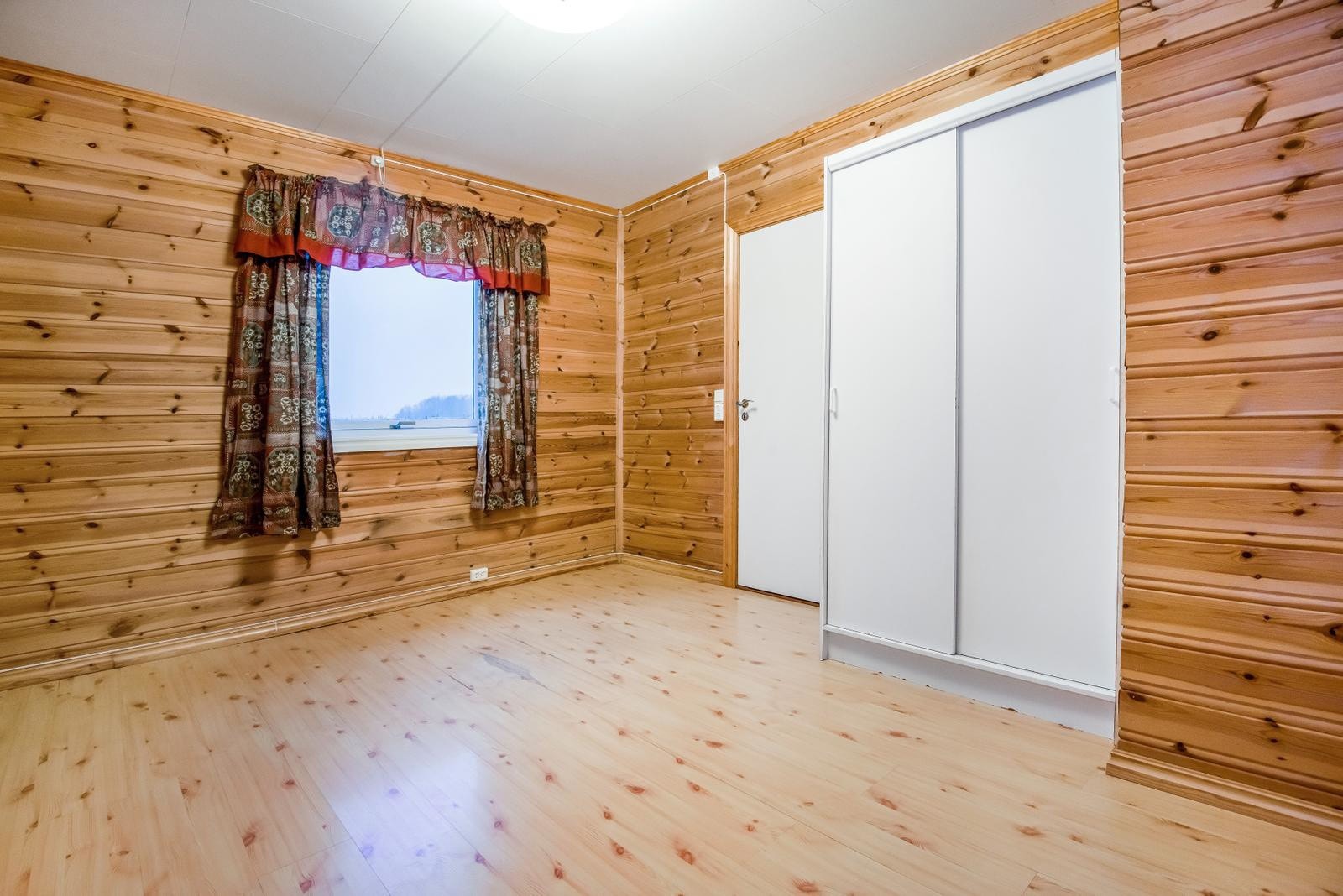 Soverommet har tregulv og panelvegger, innebygd garderobeskap og naturlig lys fra vindu. Galleribilde