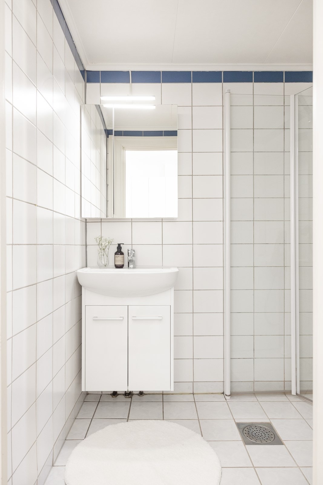 Flislagt bad med servant, speilskap, dusj og opplegg til vaskemaskin. Galleribilde