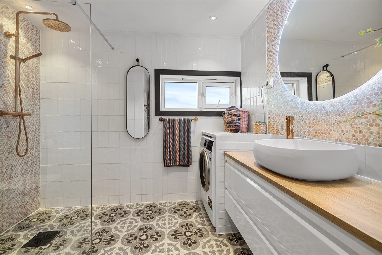 Badet er innredet med vegghengt toalett og en stor baderomsinnredning med frittstående servant og lysspeil Galleribilde