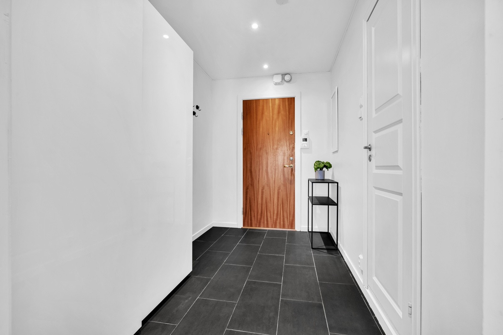 Entreén er lys og har hvitmalte vegger og himling med downlights, samt mørke grå fliser på gulv. Det er også montert calling-anlegg ved inngangspartiet. Galleribilde