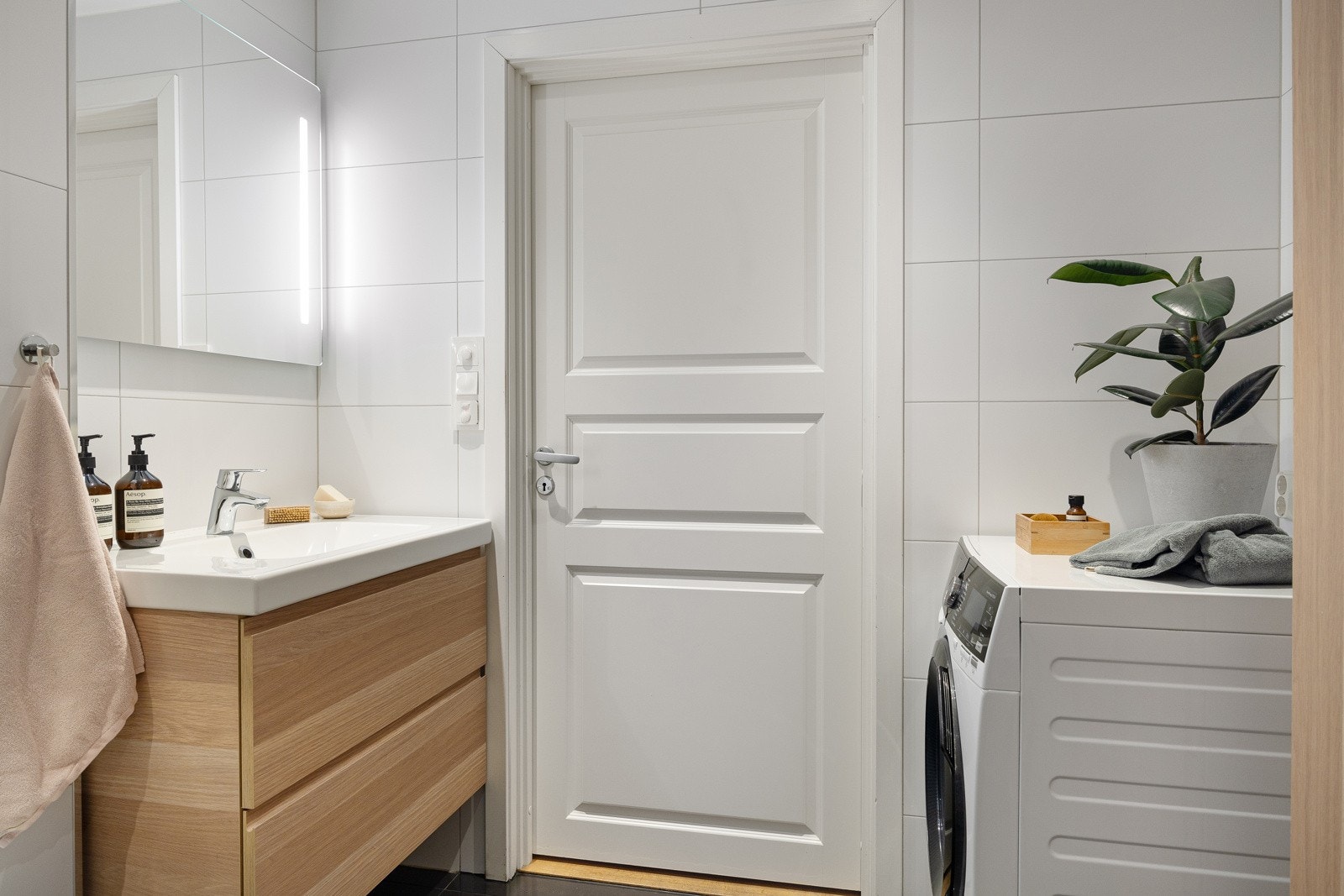 Inneholder: Heldekkende servant med skuffer, speil med integrert belysning, veggmontert skap, dusjhjørne, vegghengt klosett og opplegg til oppvaskmaskin/tørketrommel. Galleribilde