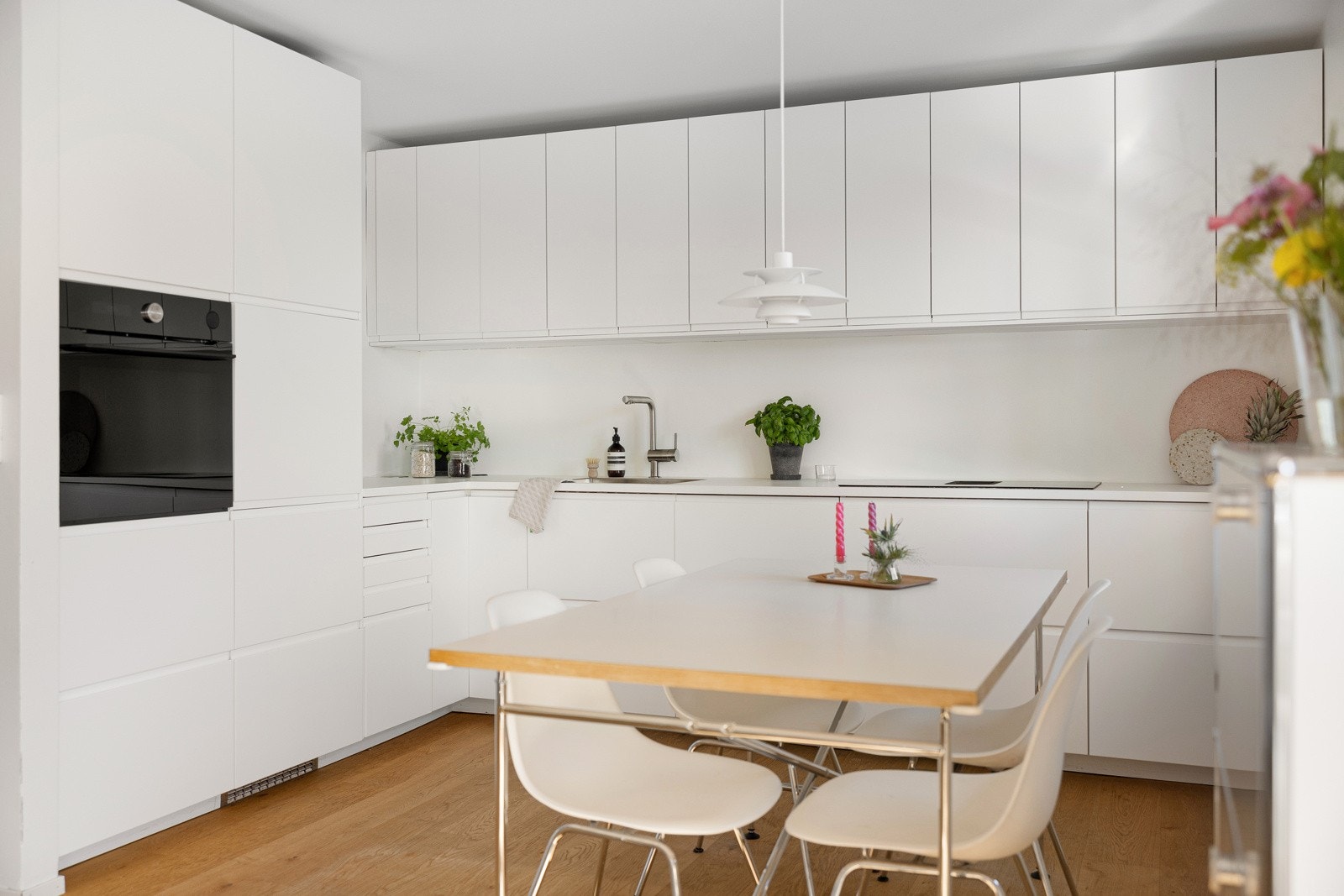 Kjøkkeninnredning med hvite glatte fronter m/ integrerte grep og benkeplate i laminat m/planlimt kum. Galleribilde