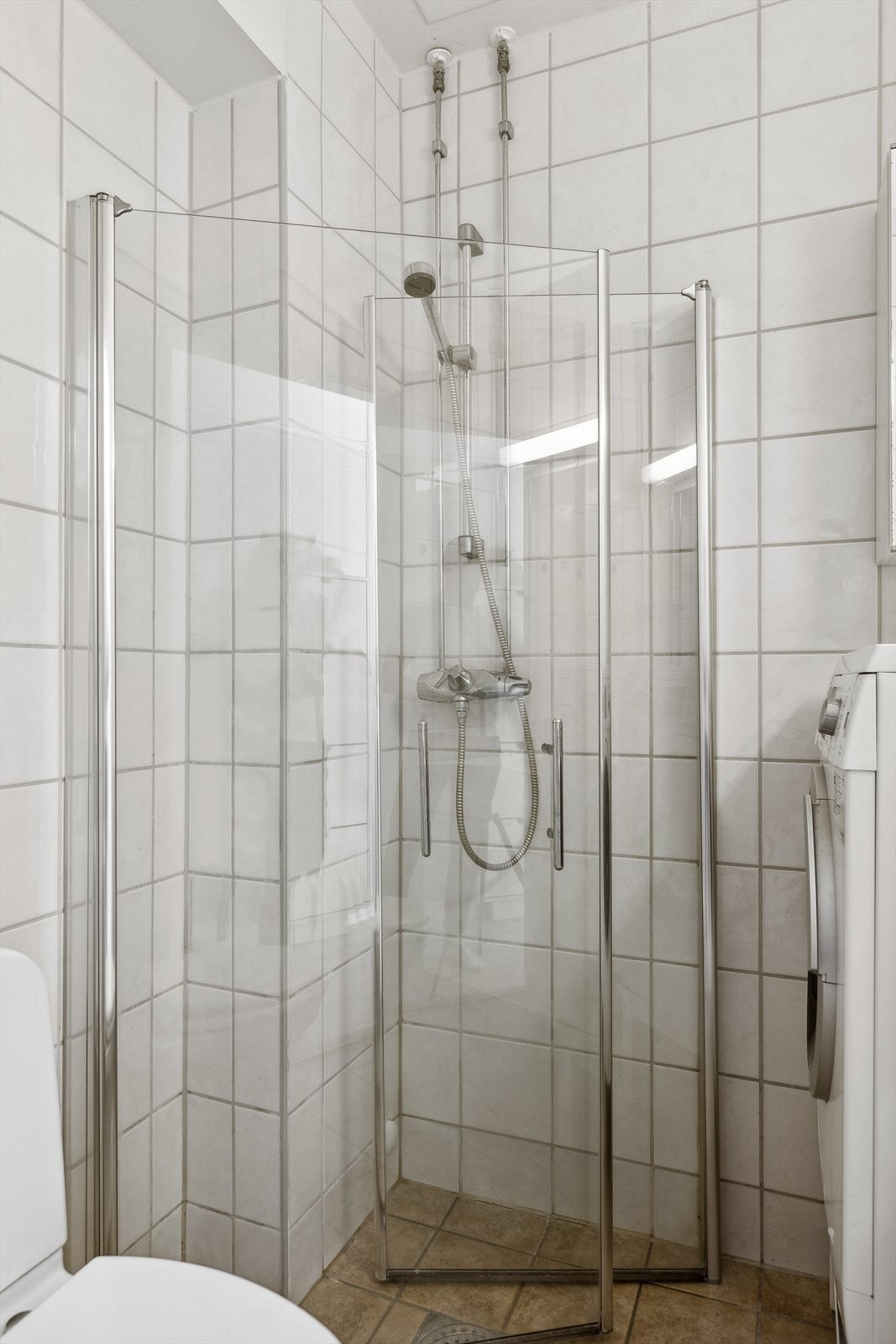 Badet er innredet med heldekkende servant på underskap med folierte fronter, speil , gulvmontert klosett og dusjhjørne med svingbare rette dusjdører. Galleribilde