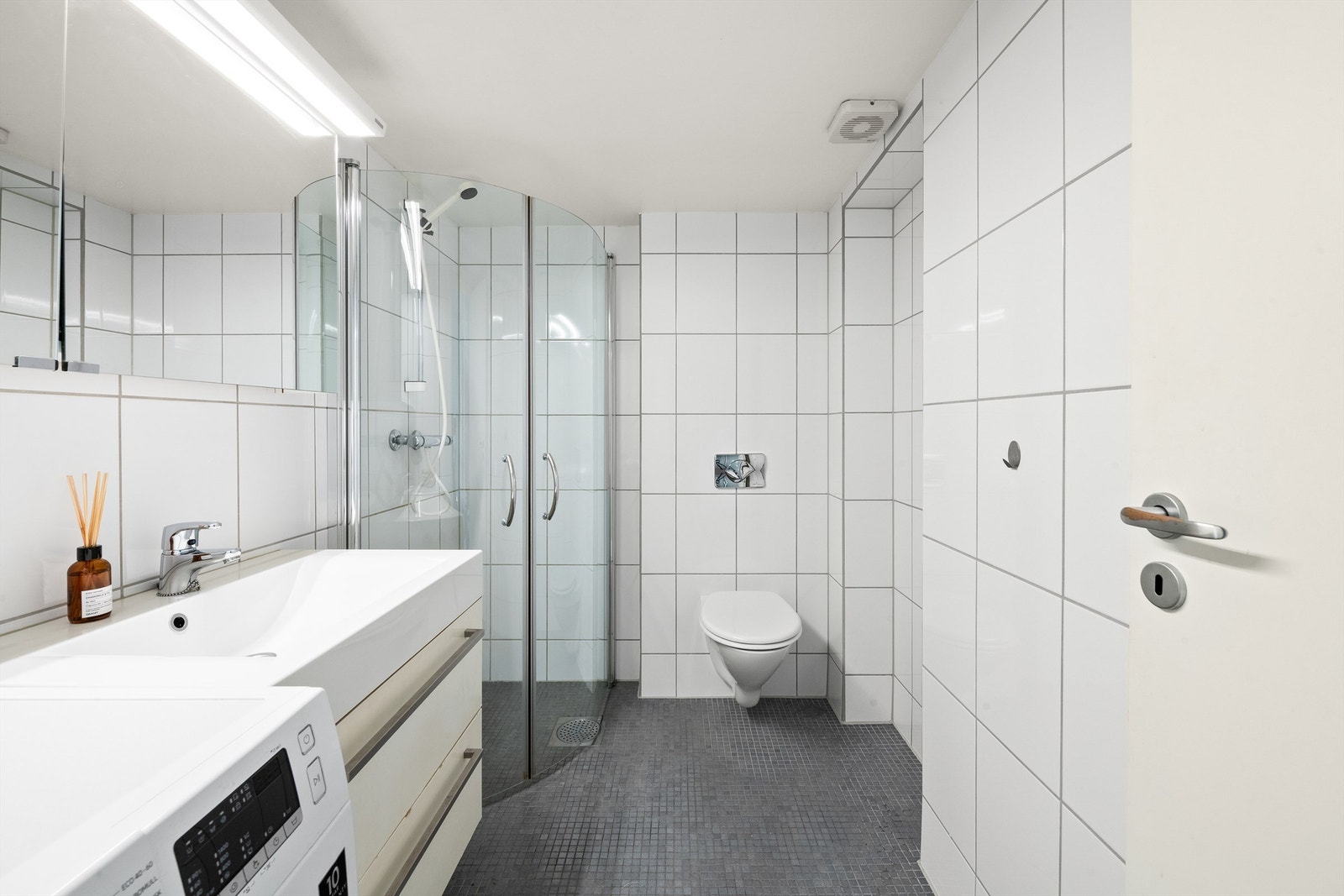 Leiligheten har et flislagt bad fra 2005 med gulvvarme. Baderommet er av god størrelse og det er plass til oppbevaring i skuffeseksjon og i skap med speilfronter montert over servant. Galleribilde