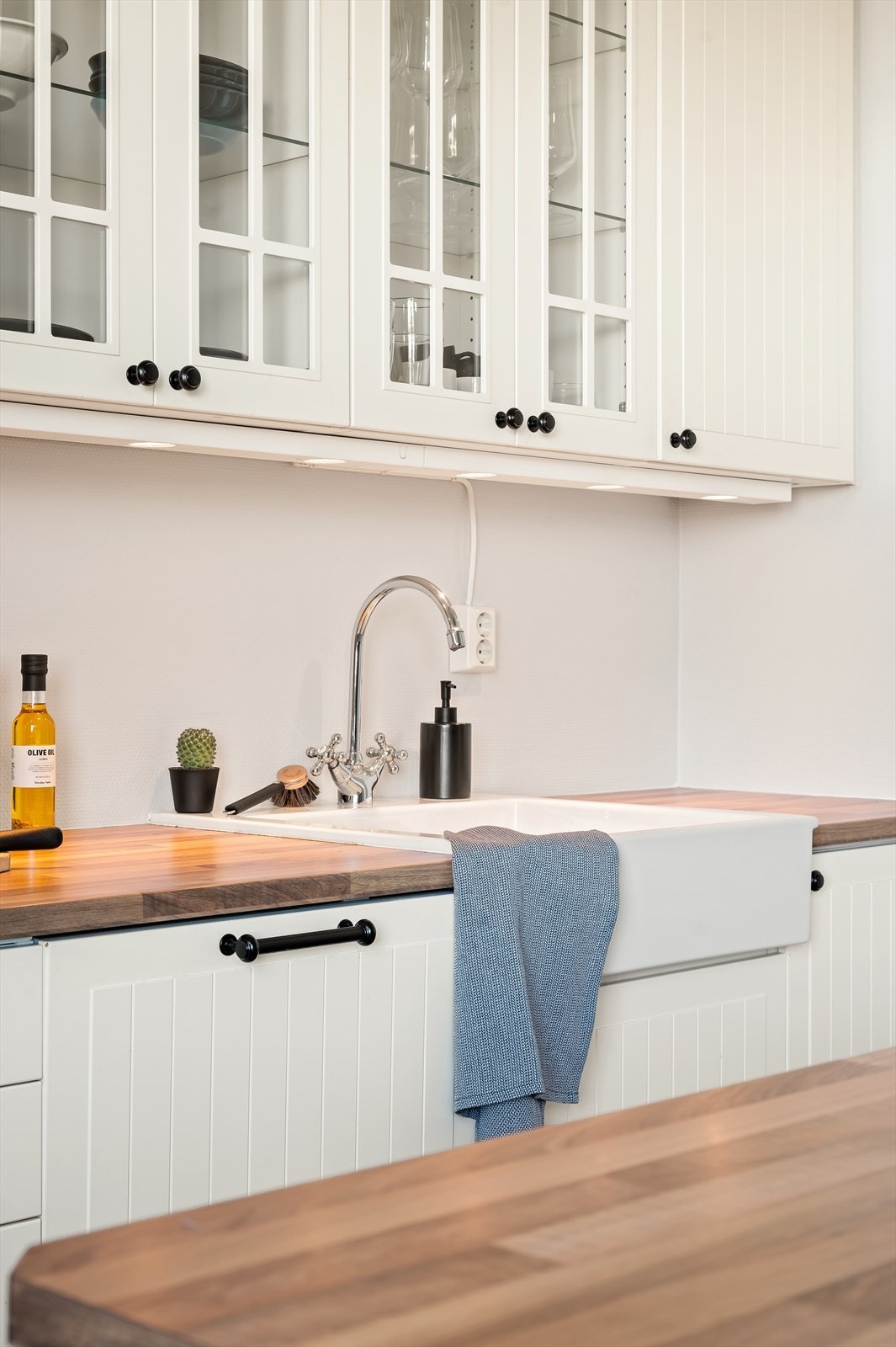 Kjøkkeninnredning med profilerte fronter, laminert benkeplate med integrert kjøkkenkum, malt vegg over kjøkkenbenk og belysning. Galleribilde