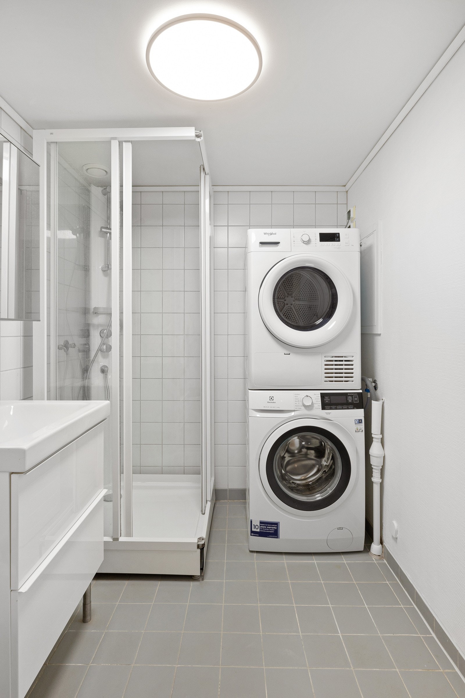 Flislagt bad med dusjkabinett og opplegg for vaskemaskin Galleribilde