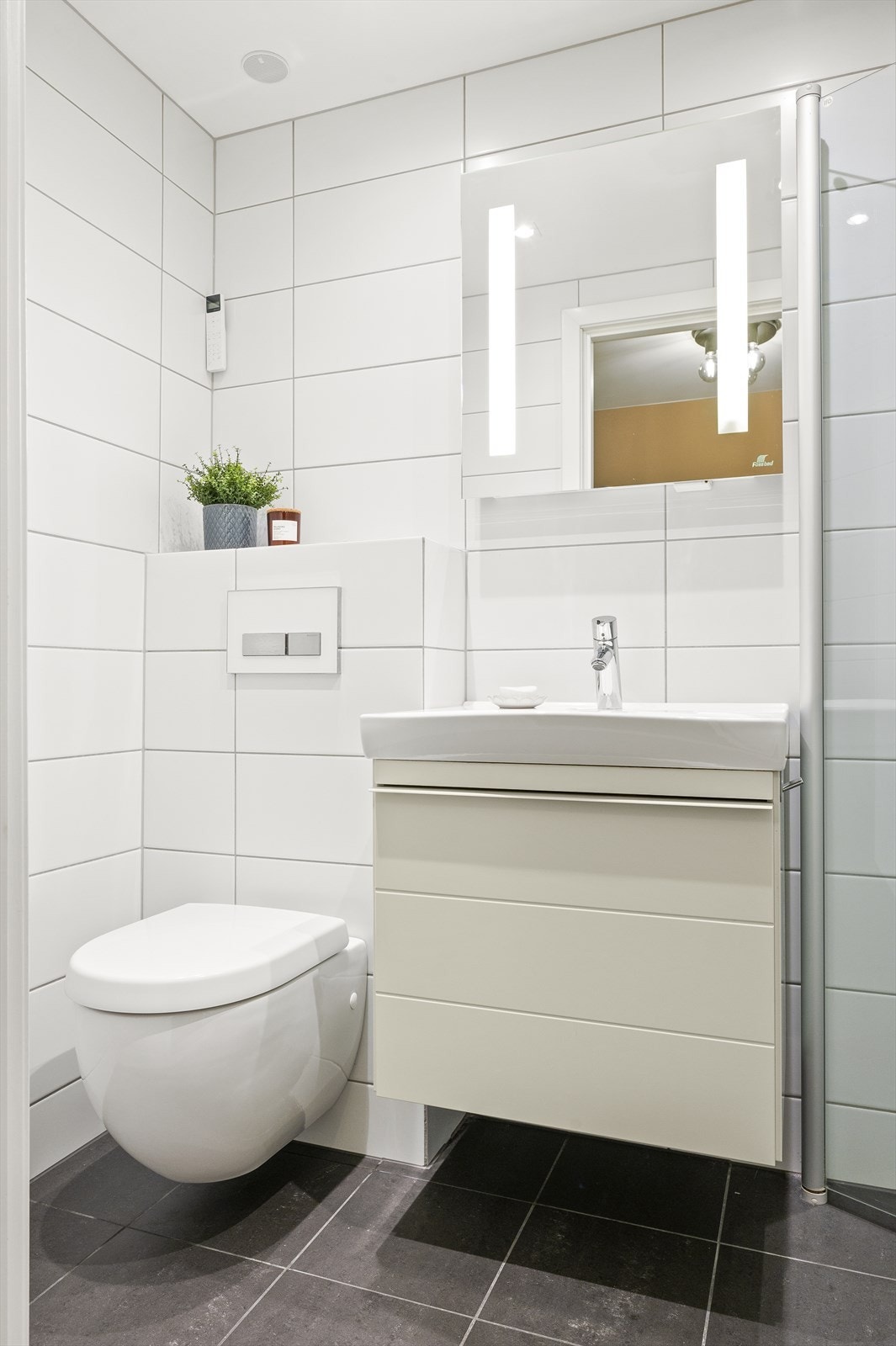 Leilighetens andre bad er også pent flislagt på gulv og vegger og er innredet med vegghengt servantskap med servant. Over servanten er det et fint speil med innebygget belysning i likhet som på bad 1. Galleribilde